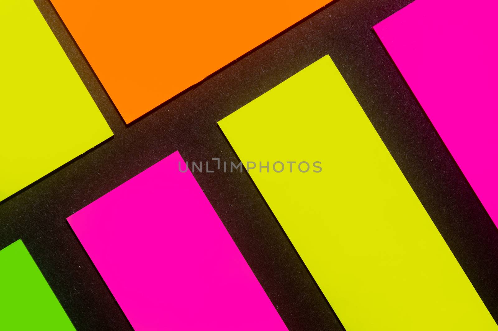 Green, yellow, orange and purple hue colorful office stickers on black paper. Office noteparer as reminder. Isolated on black paper.