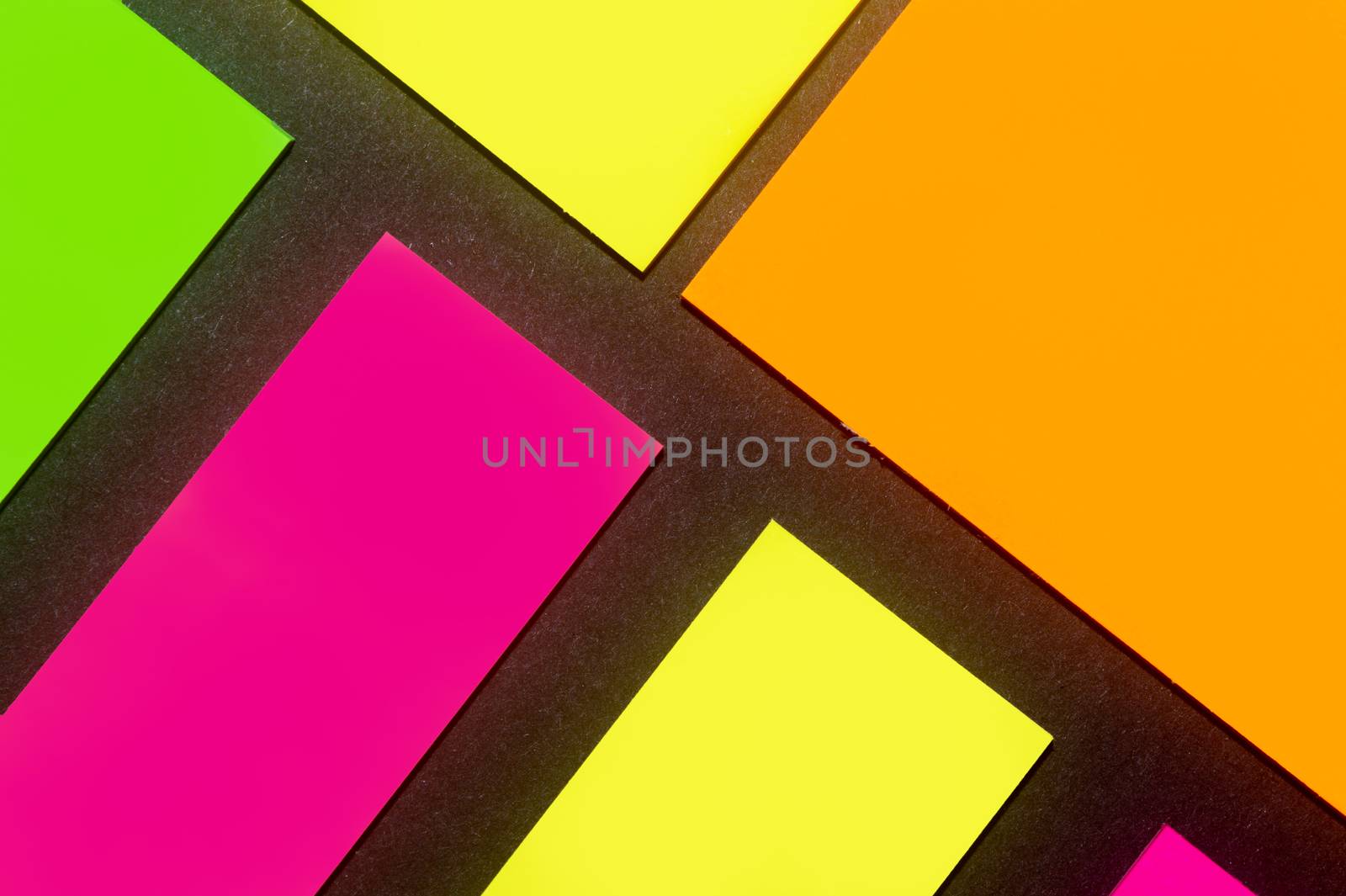 Green, yellow, orange and purple hue colorful office stickers on black paper. Office noteparer as reminder. Isolated on black paper.