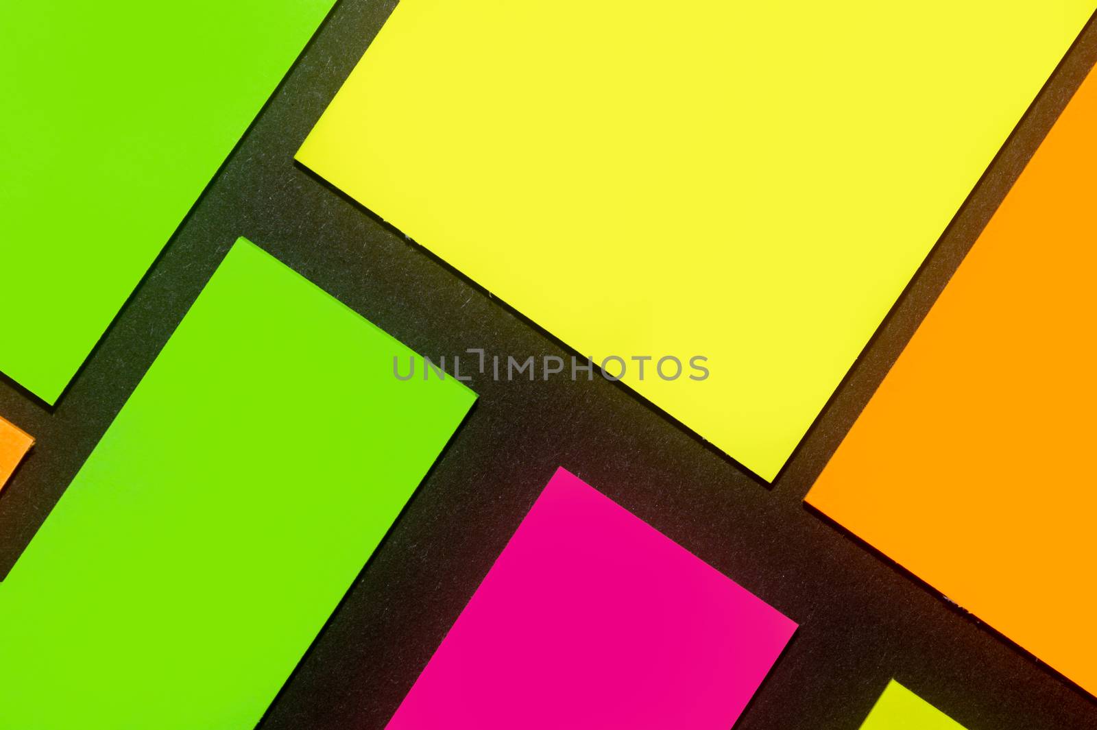 Green, yellow, orange and purple hue colorful office stickers on black paper. Office noteparer as reminder. Isolated on black paper.