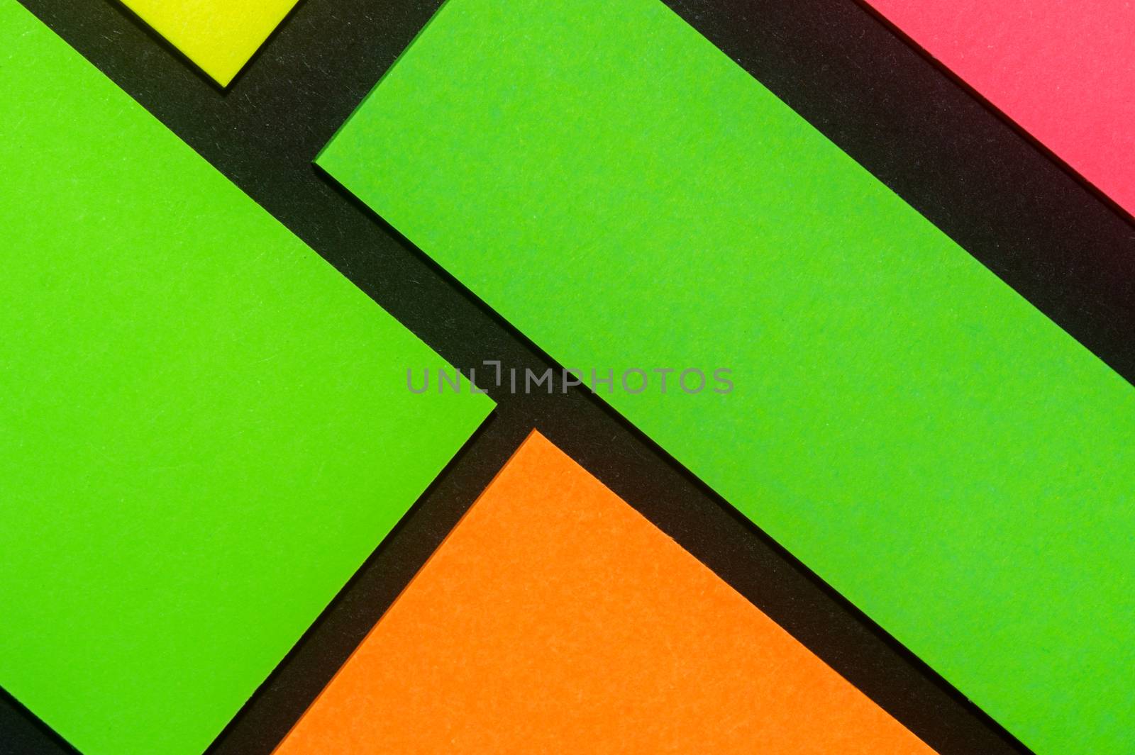 Green, yellow, orange and rose hue colorful office stickers on black paper. Office noteparer as reminder. Isolated on black paper.