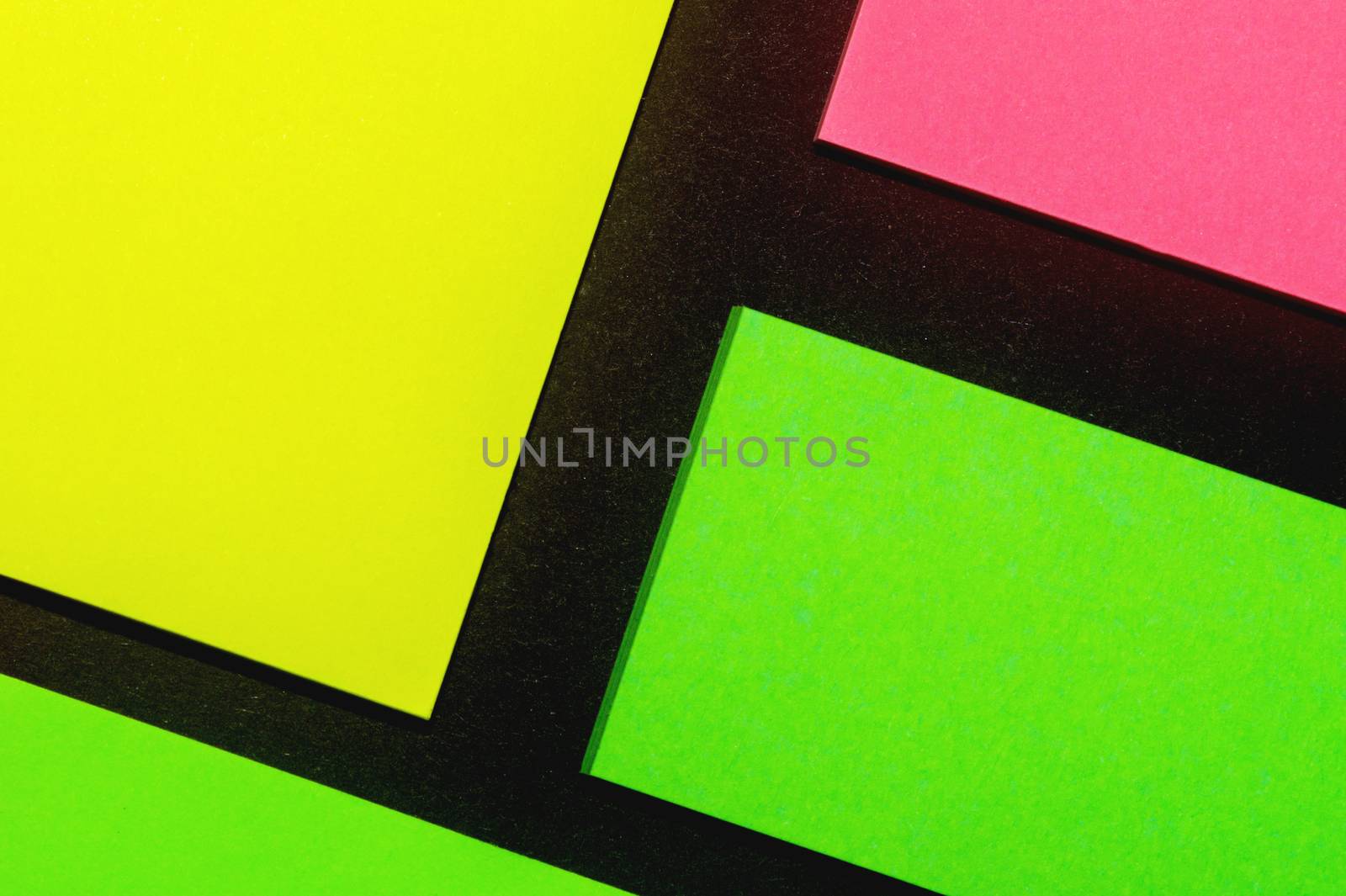 Green, yellow and rose hue colorful office stickers on black paper. Office noteparer as reminder. Isolated on black paper.