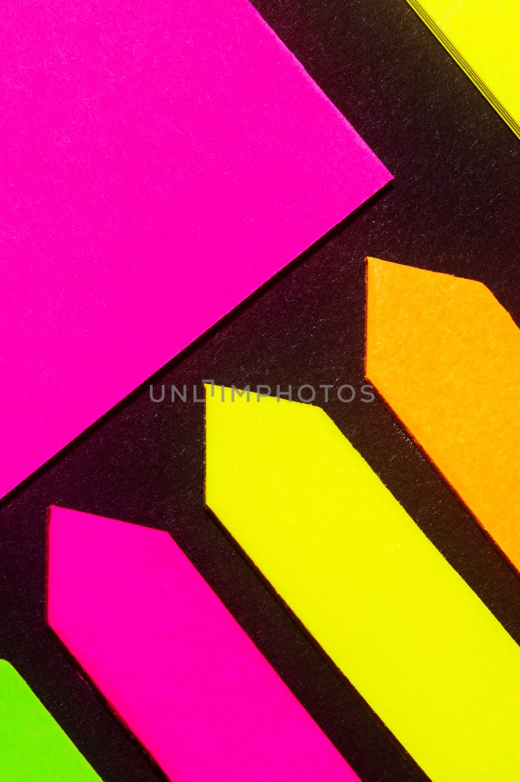 Green, yellow, orange and purple hue colorful office stickers on black paper. Office noteparer as reminder. Isolated on black paper. by alexsdriver