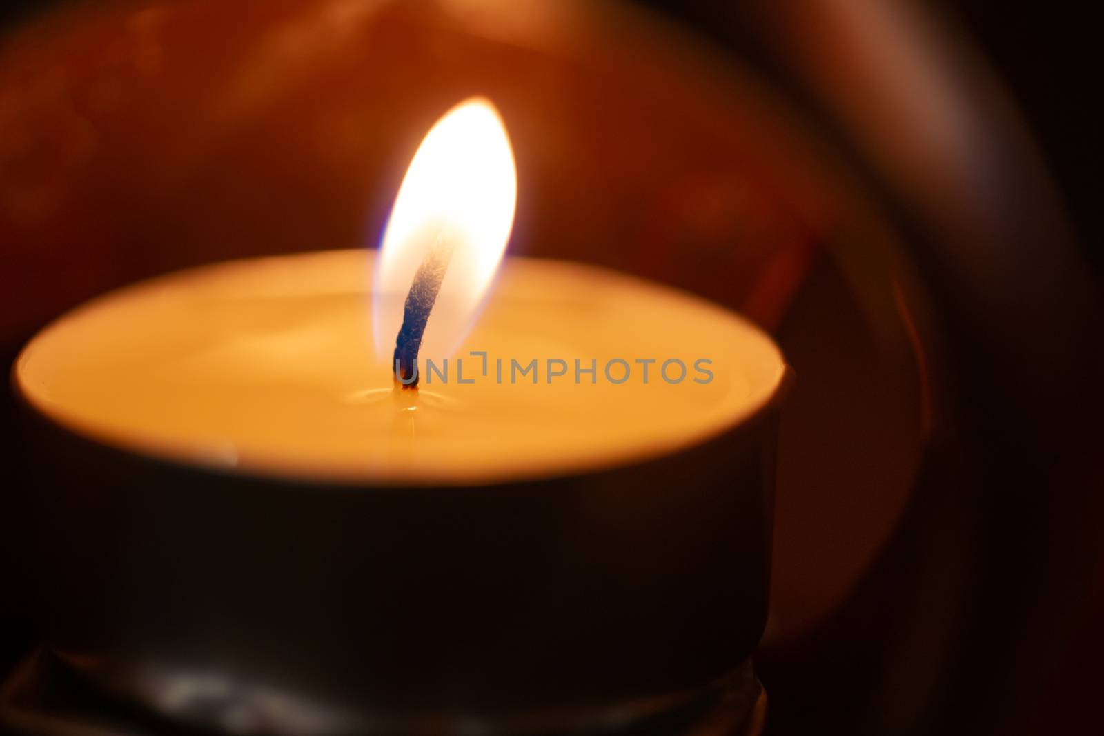 Underexposed low light photo of candle in aromatic lamp. Close-up view