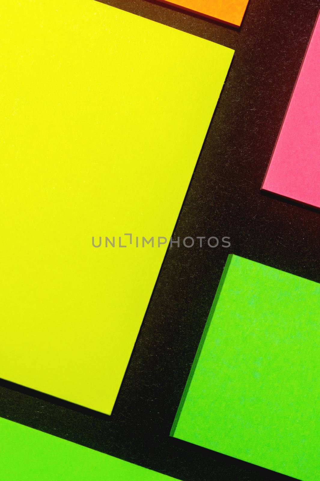 Green, yellow, orange and rose hue colorful office stickers on black paper. Office noteparer as reminder. Isolated on black paper.