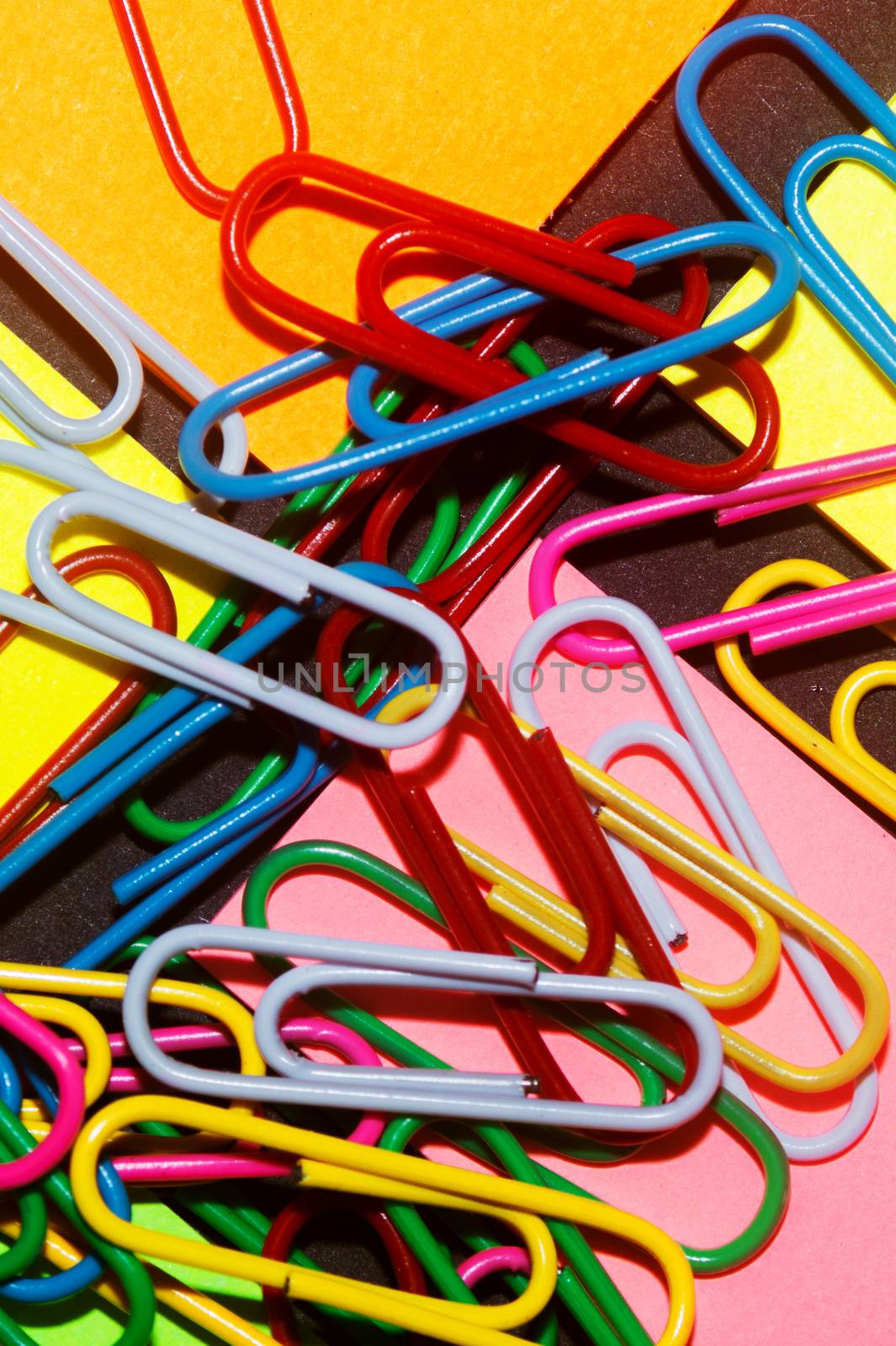 Paperclips on colorful different colour office stickers on black paper. by alexsdriver