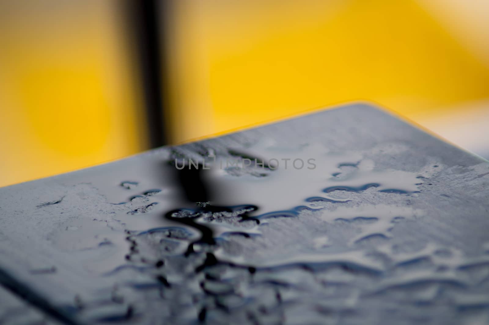 Black wood table after rain on yellow background. Many water rain drops on table. the bred is black. by alexsdriver