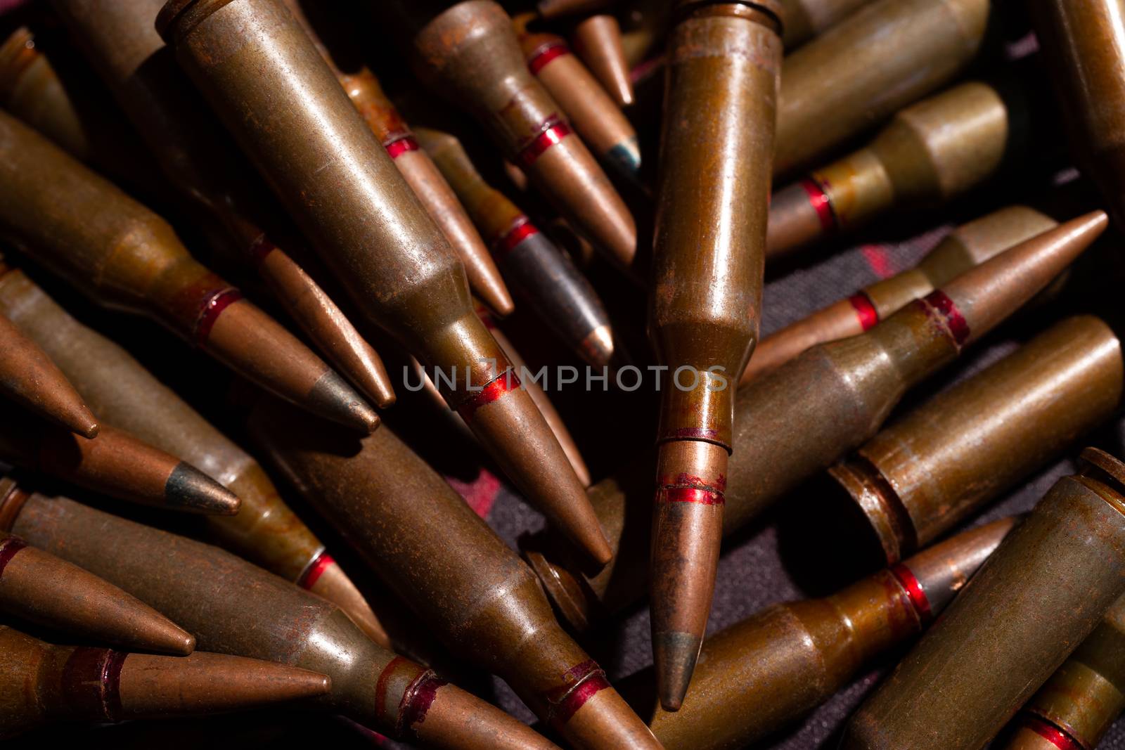 A lot of rifle ammo. AK-47 bullet cartridge. Armor piercing cartridge close up view. Underexposed photo. by alexsdriver
