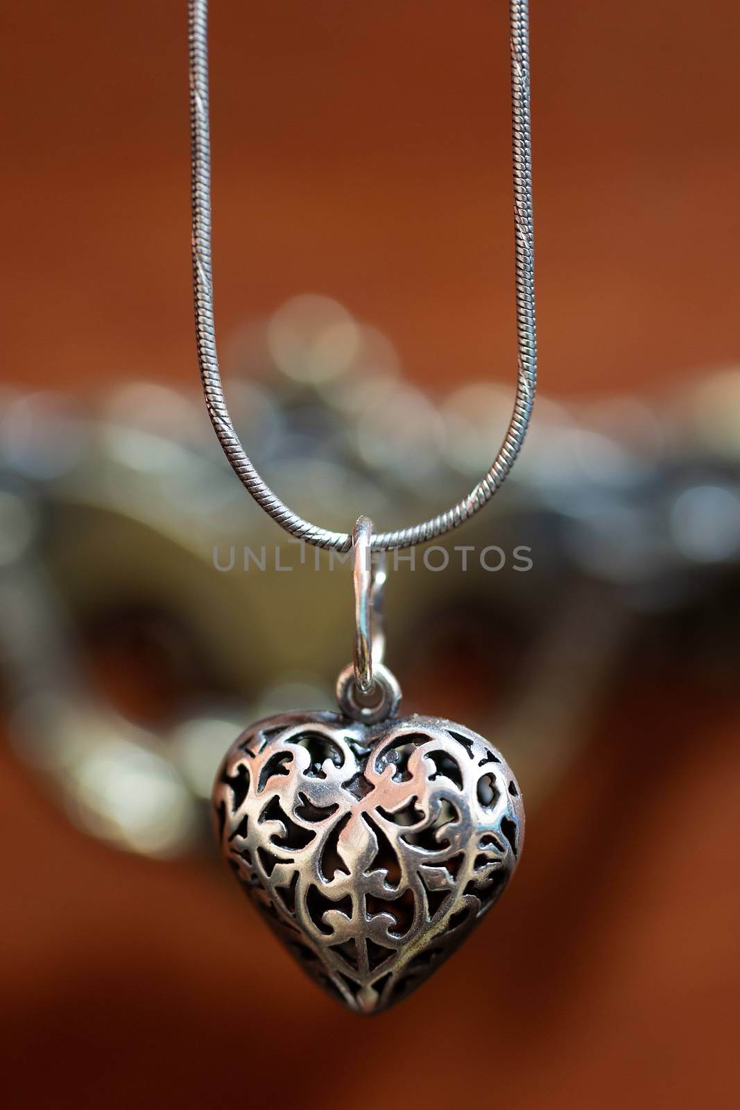 Close up photo of female neck silver pendand on blurred background. A handwork sterling silver pendant look as heart. Macrophoto with blurred background. by alexsdriver