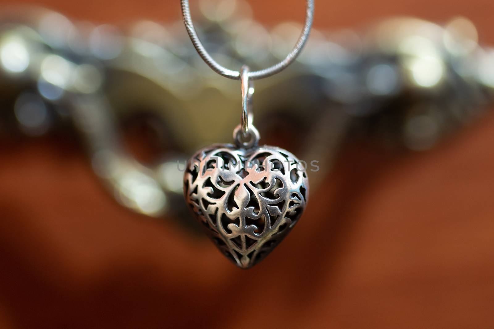 Close up photo of female neck silver pendand on blurred background. A handwork sterling silver pendant look as heart. Macrophoto with blurred background. by alexsdriver