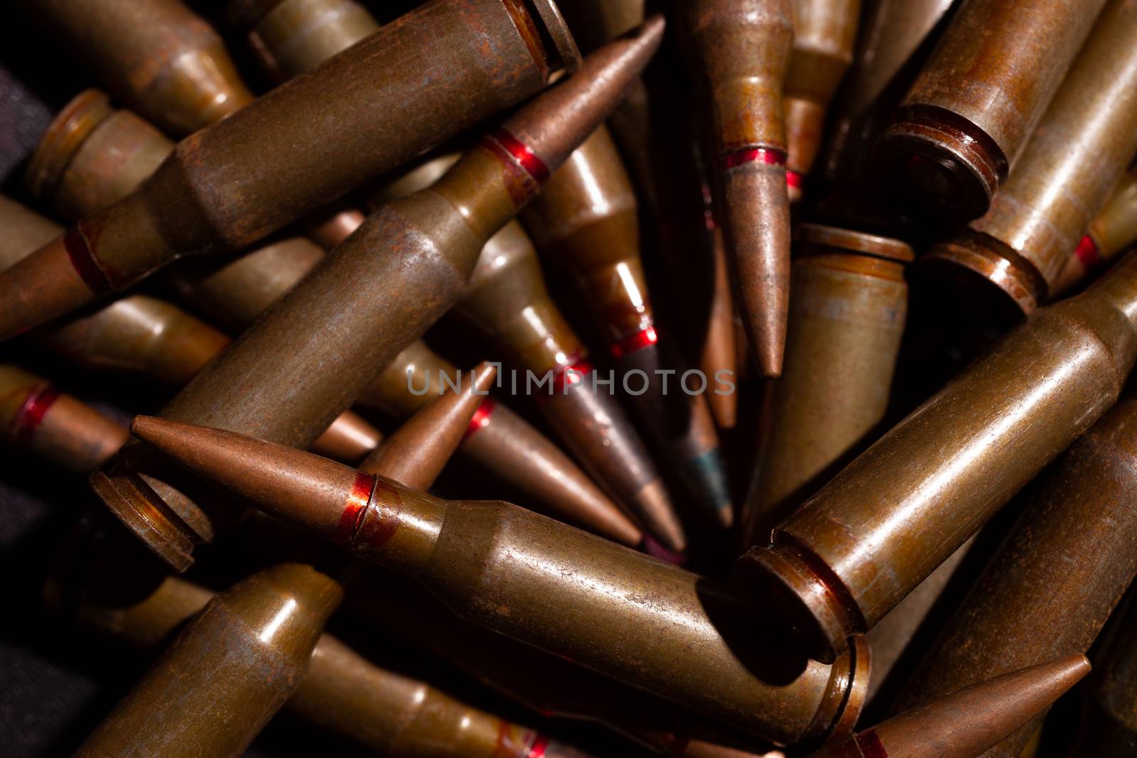 A lot of rifle ammo. AK-47 bullet cartridge. Armor piercing cartridge close up view. Underexposed photo. by alexsdriver