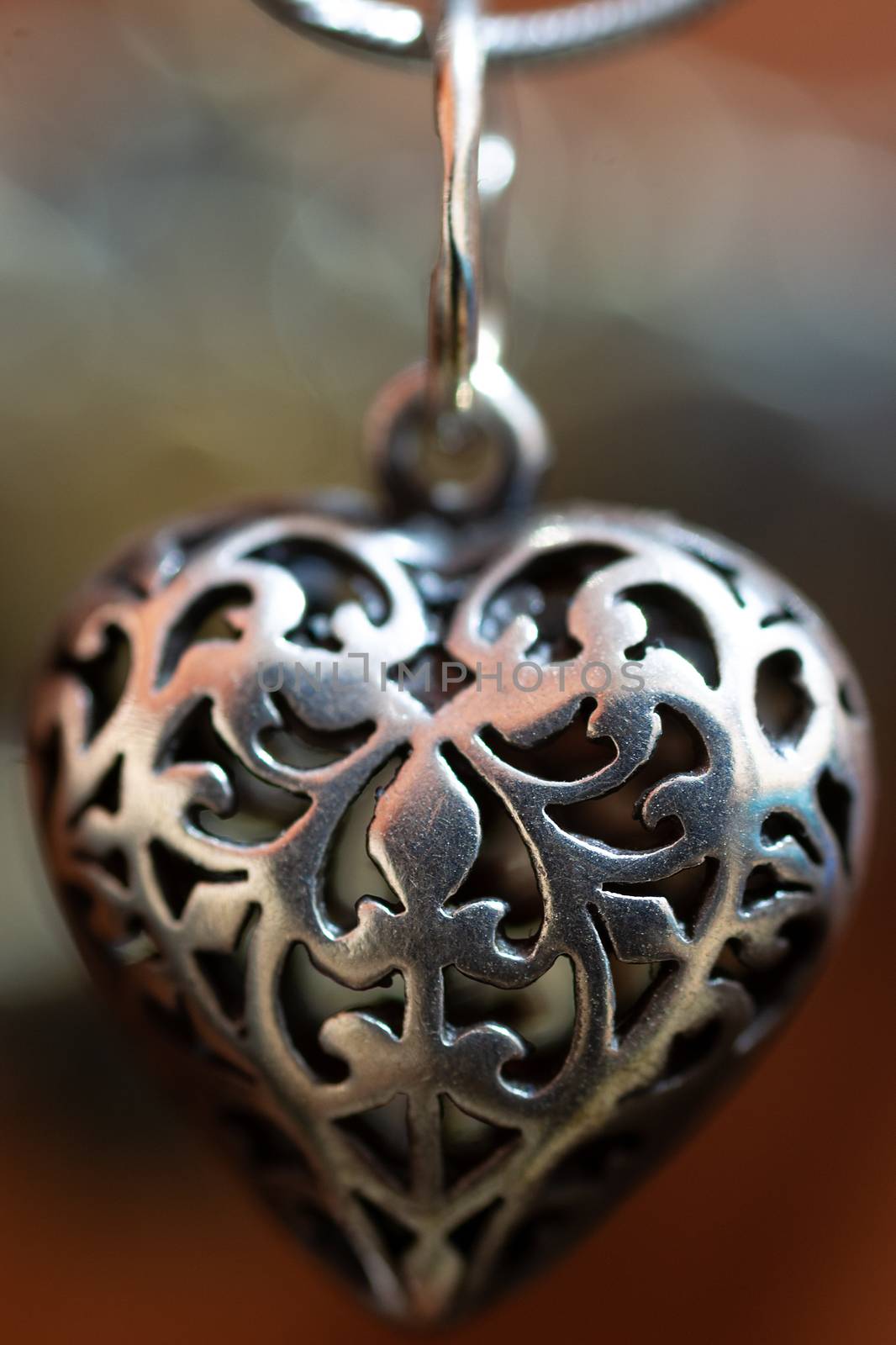 Close up photo of female neck silver pendand on blurred background. A handwork sterling silver pendant look as heart. Macrophoto with blurred background.