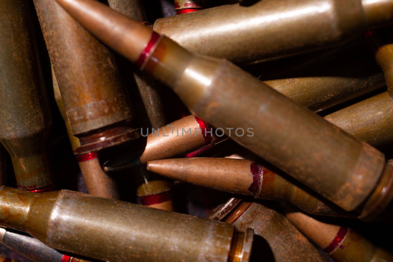 A lot of rifle ammo. AK-47 bullet cartridge. Armor piercing cartridge close up view. Underexposed photo. by alexsdriver