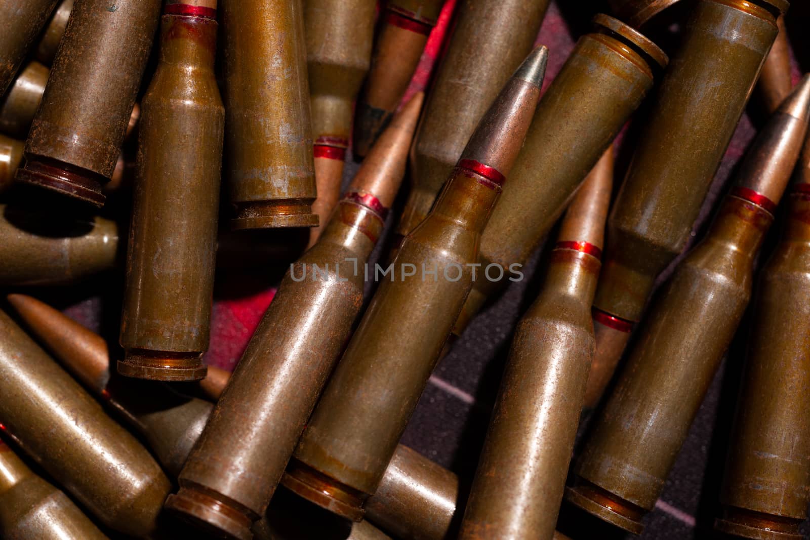 A lot of rifle ammo. AK-47 bullet cartridge. Armor piercing cartridge close up view. Underexposed photo. by alexsdriver