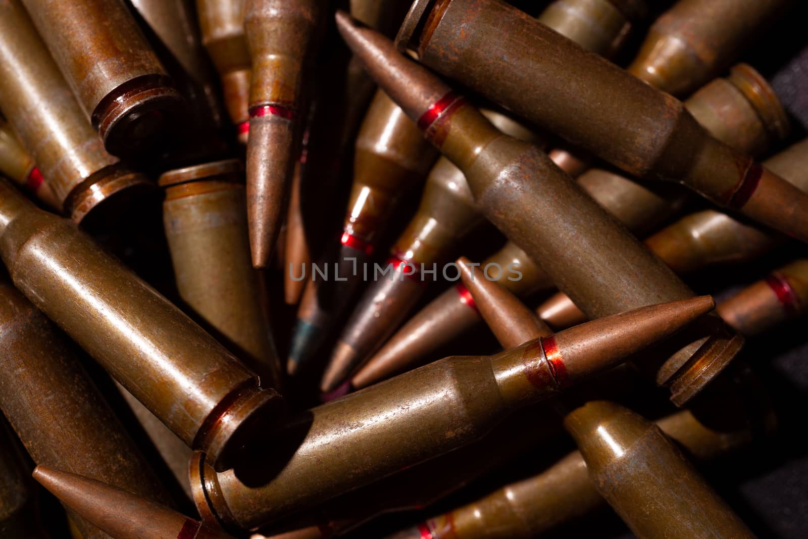 A lot of rifle ammo. AK-47 bullet cartridge. Armor piercing cartridge close up view. Underexposed photo.