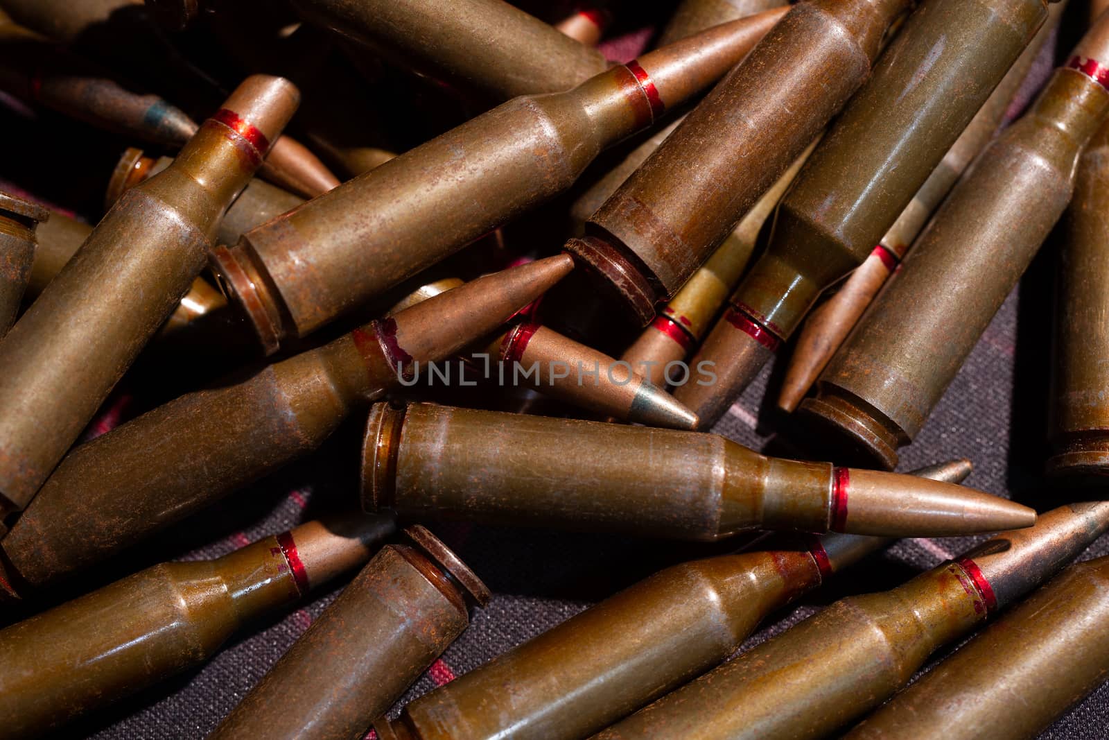 A lot of rifle ammo. AK-47 bullet cartridge. Armor piercing cartridge close up view. Underexposed photo. by alexsdriver