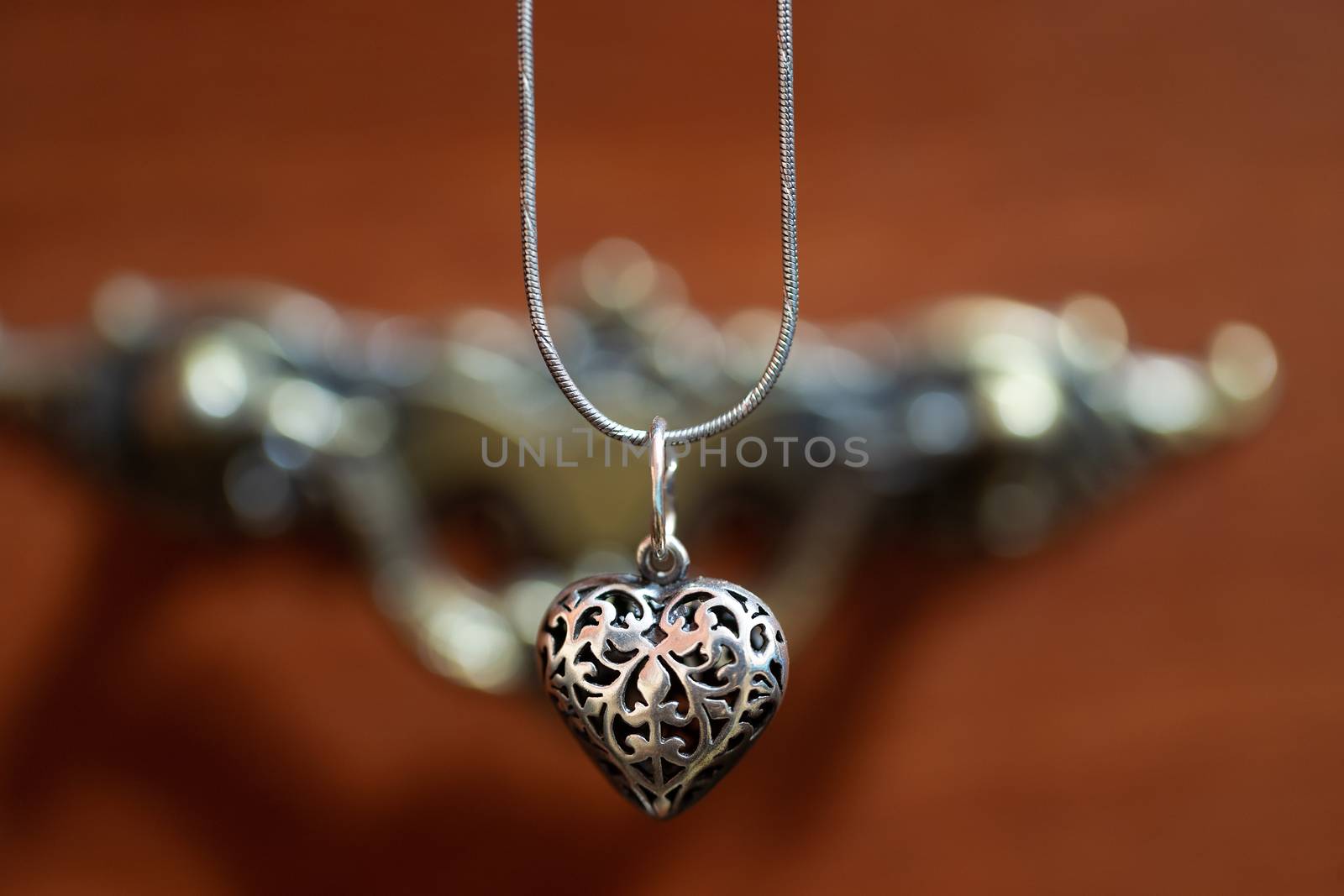 Close up photo of female neck silver pendand on blurred background. A handwork sterling silver pendant look as heart. Macrophoto with blurred background. by alexsdriver