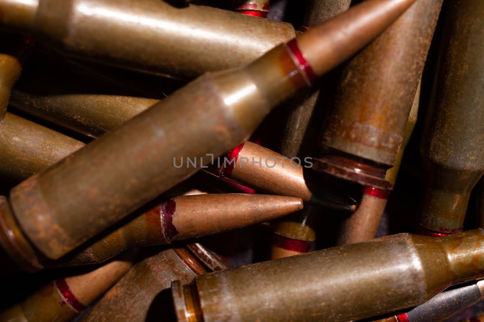 A lot of rifle ammo. AK-47 bullet cartridge. Armor piercing cartridge close up view. Underexposed photo. by alexsdriver