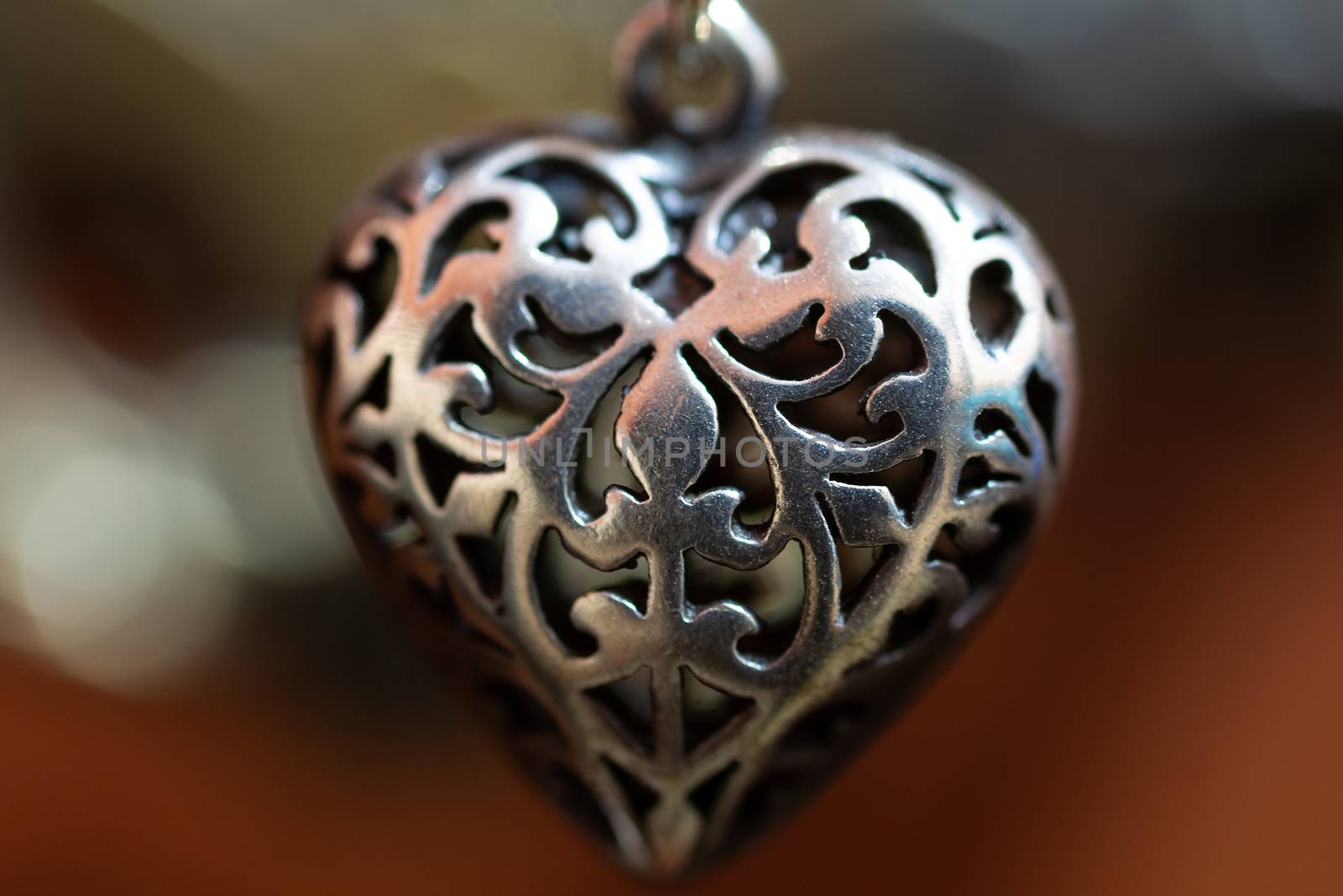 Close up photo of female neck silver pendand on blurred background. A handwork sterling silver pendant look as heart. Macrophoto with blurred background. by alexsdriver