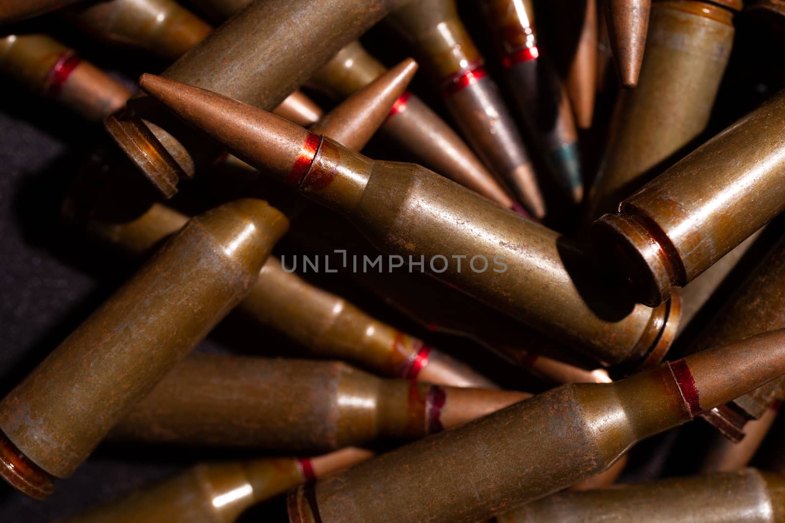 A lot of rifle ammo. AK-47 bullet cartridge. Armor piercing cartridge close up view. Underexposed photo.