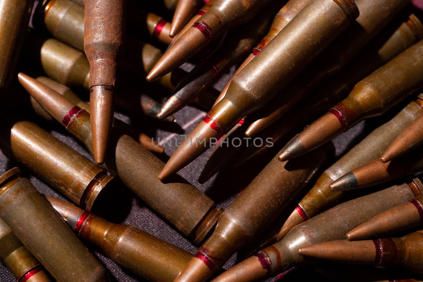 A lot of rifle ammo. AK-47 bullet cartridge. Armor piercing cartridge close up view. Underexposed photo.