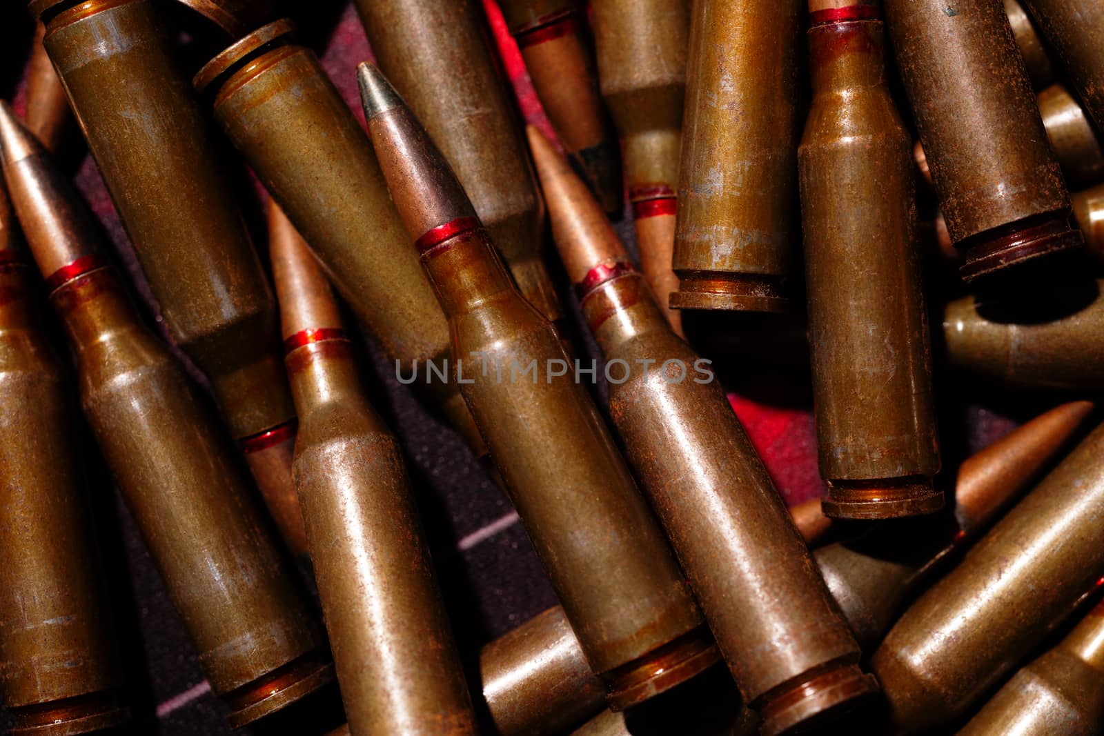 A lot of rifle ammo. AK-47 bullet cartridge. Armor piercing cartridge close up view. Underexposed photo. by alexsdriver