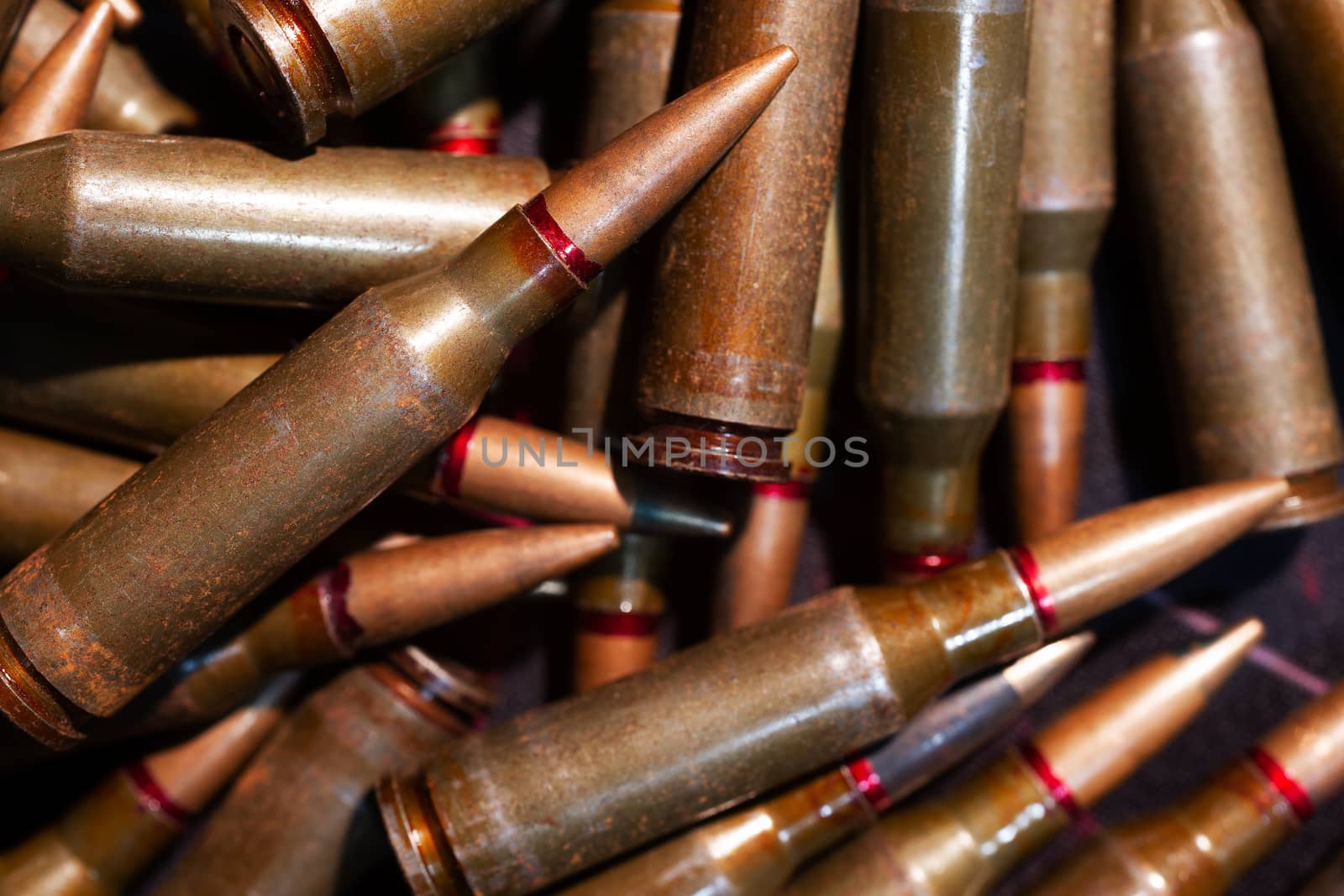 A lot of rifle ammo. AK-47 bullet cartridge. Armor piercing cartridge close up view. Underexposed photo. by alexsdriver