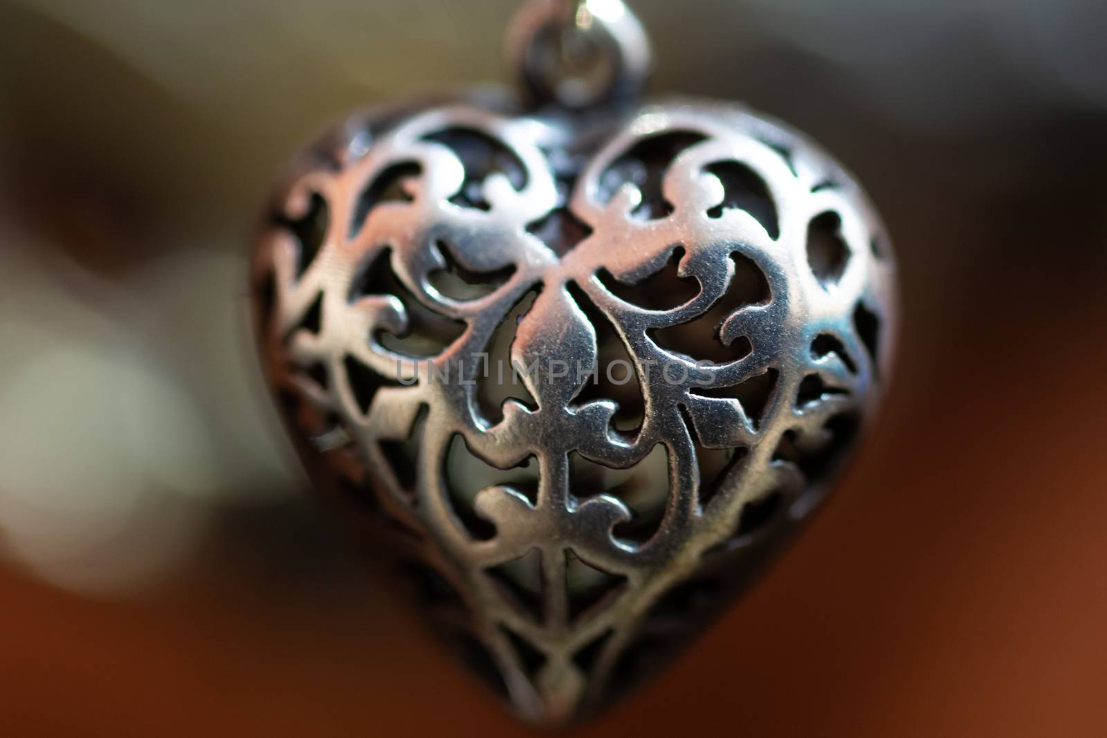 Close up photo of female neck silver pendand on blurred background. A handwork sterling silver pendant look as heart. Macrophoto with blurred background.