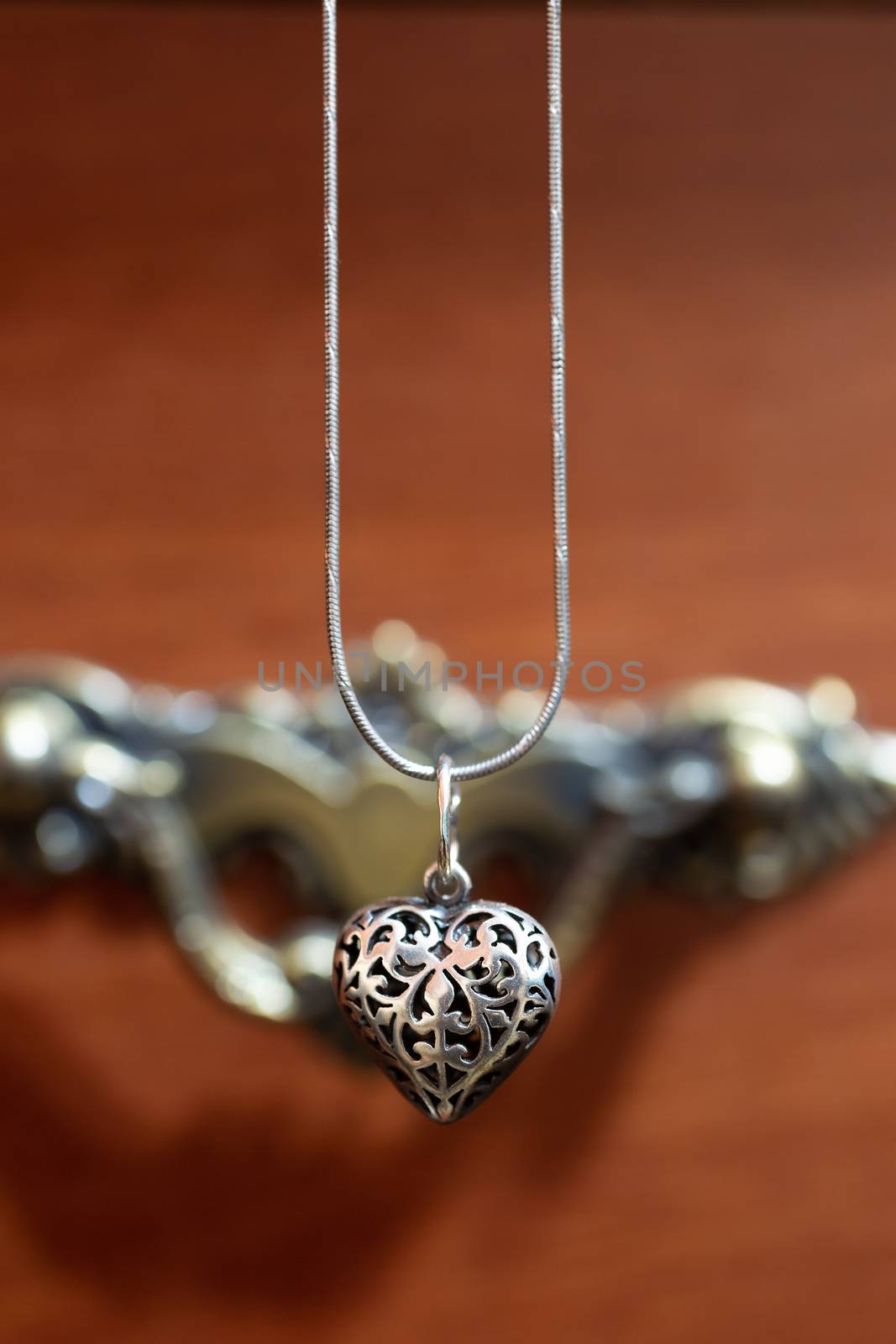 Close up photo of female neck silver pendand on blurred background. A handwork sterling silver pendant look as heart. Macrophoto with blurred background. by alexsdriver