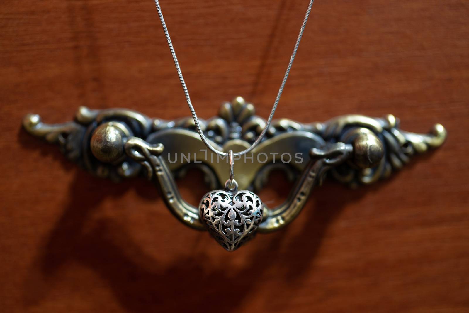 Close up photo of female neck silver pendand on blurred background. A handwork sterling silver pendant look as heart. Macrophoto with blurred background. by alexsdriver
