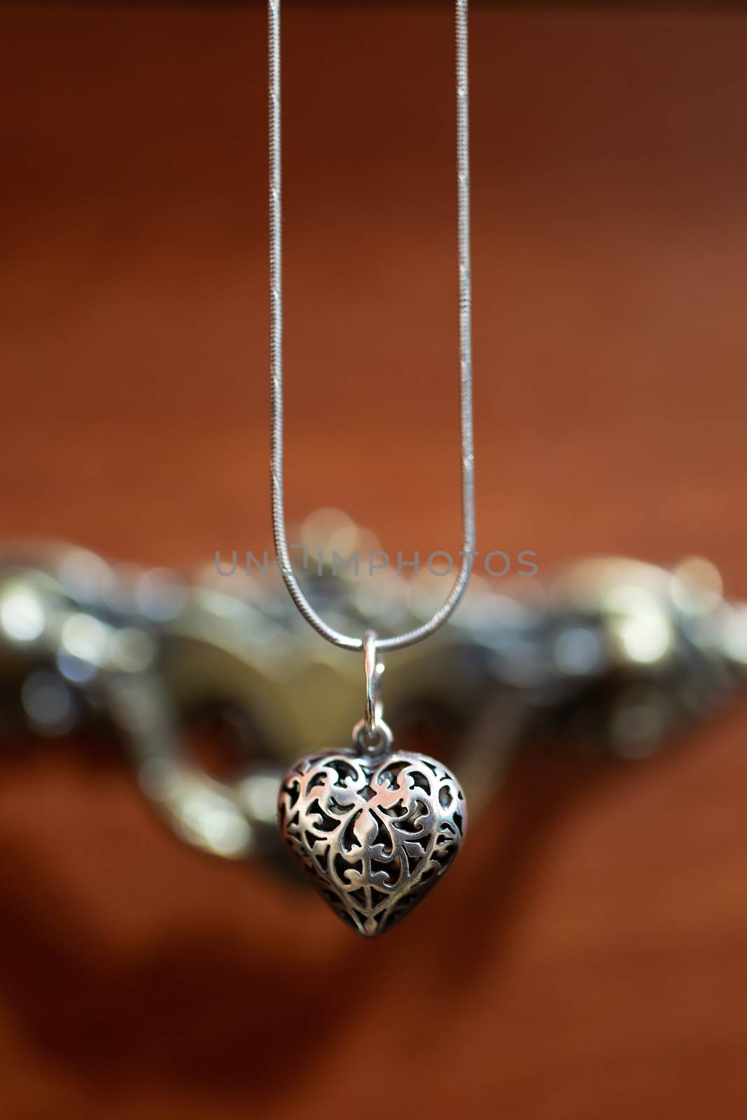 Close up photo of female neck silver pendand on blurred background. A handwork sterling silver pendant look as heart. Macrophoto with blurred background. by alexsdriver