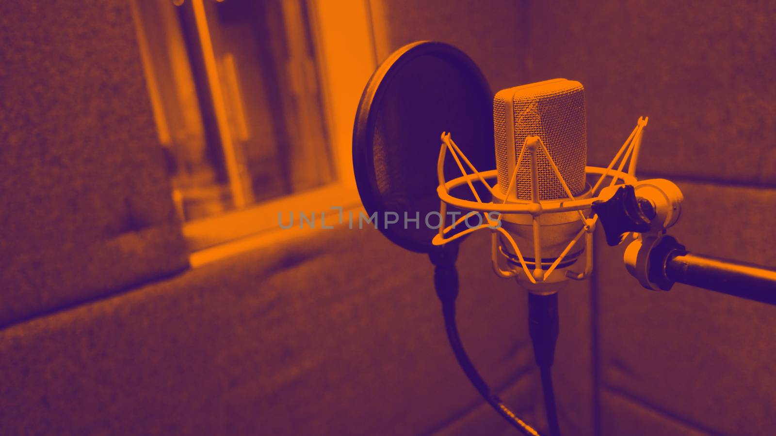 Studio microphone with shock mount and pop filter on professional tripod in acoustic foam room for best sound production on air and mix process in music industry and high quality broadcasting