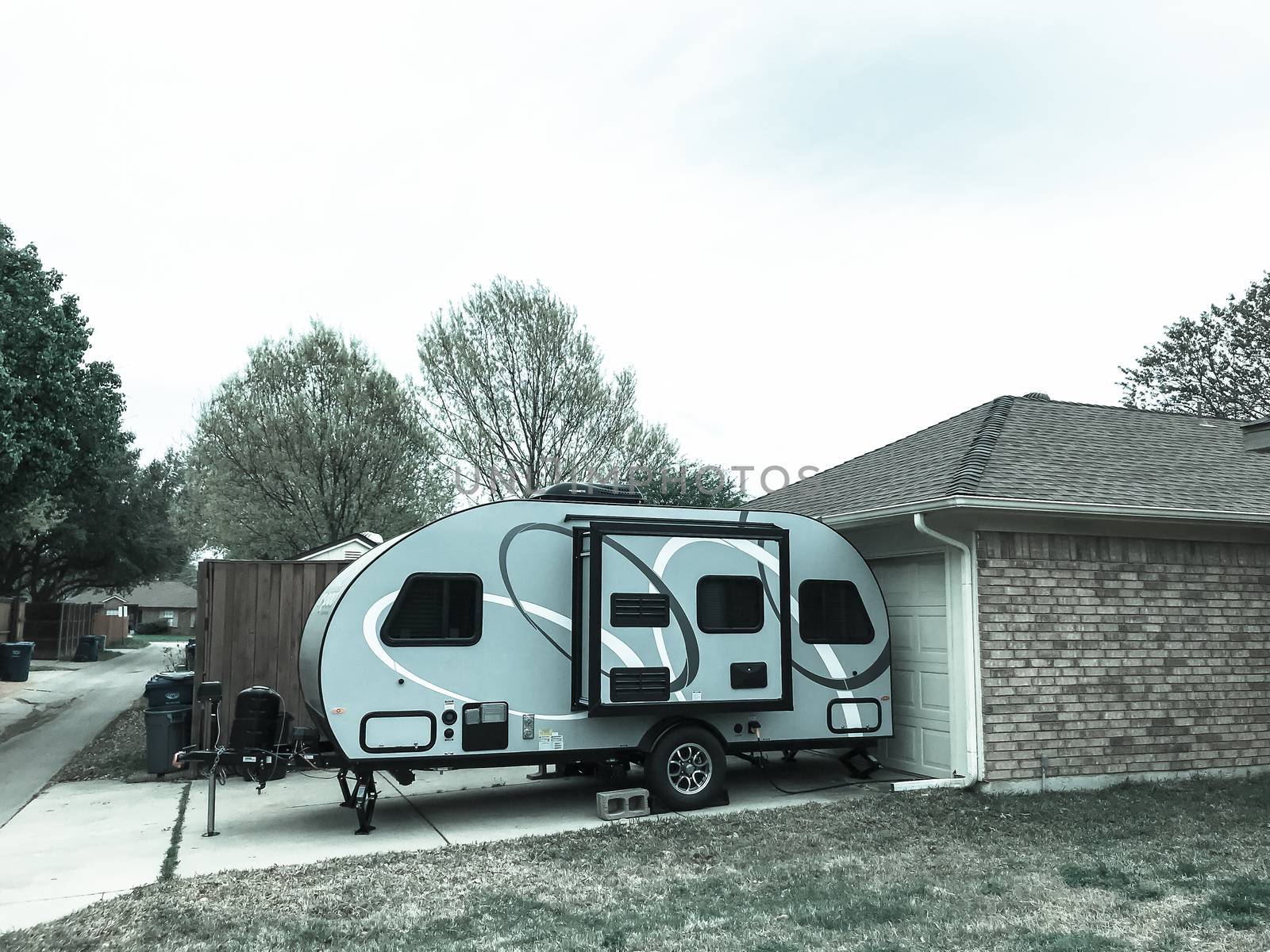 RV trailer parked at backyard of single family house, side view by trongnguyen