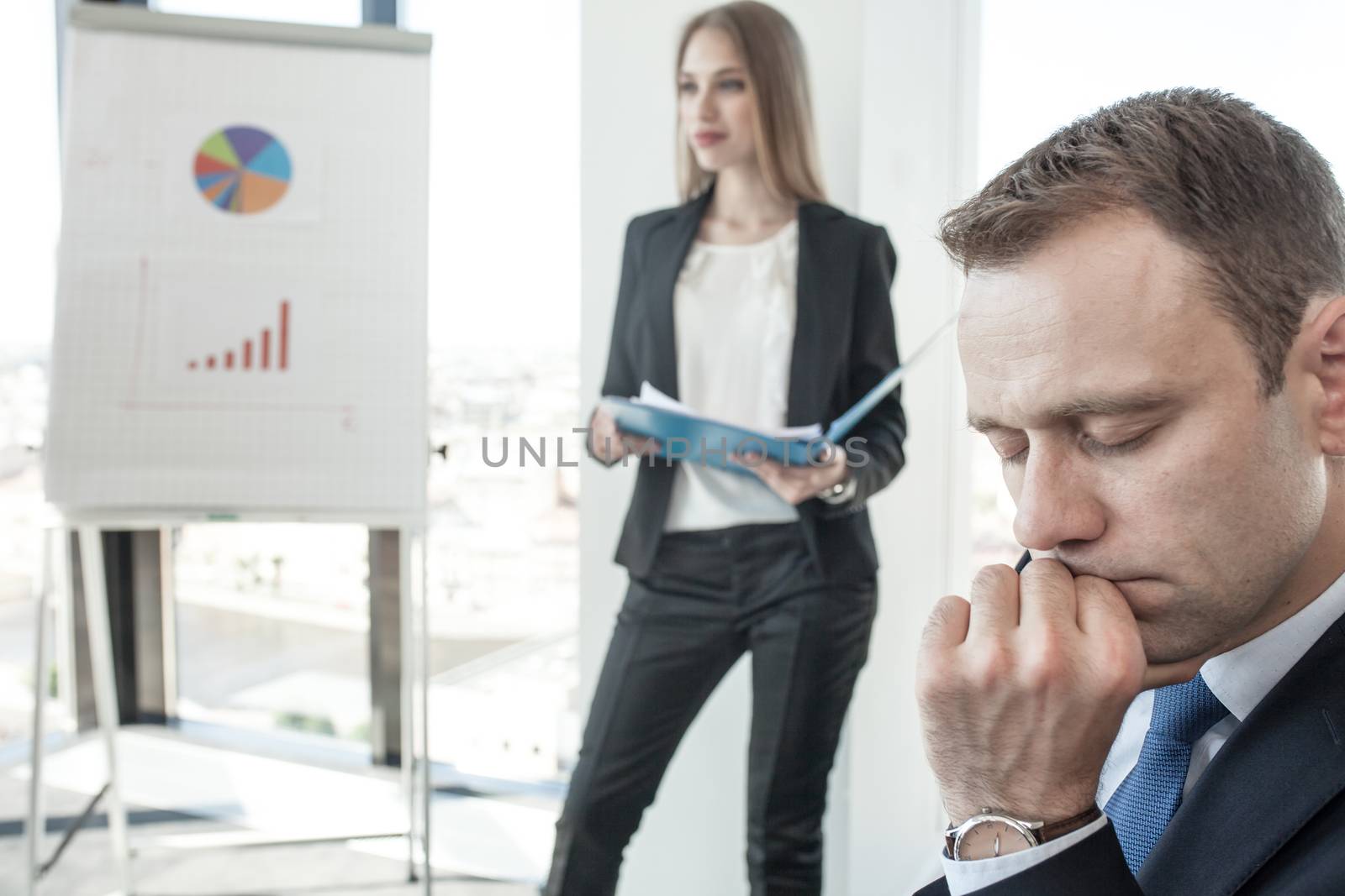 Business man with eyes closed thinking about problem solution at meeting in office