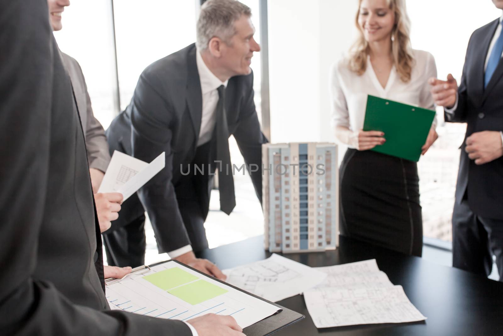 Business meeting of architects and investors, model of modern multi storey residential building house on table , construction planning concept