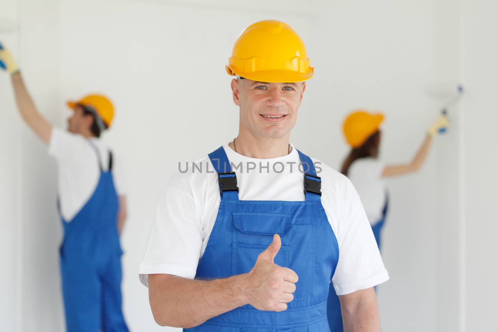 Workman gives thumbs up in front of two painters