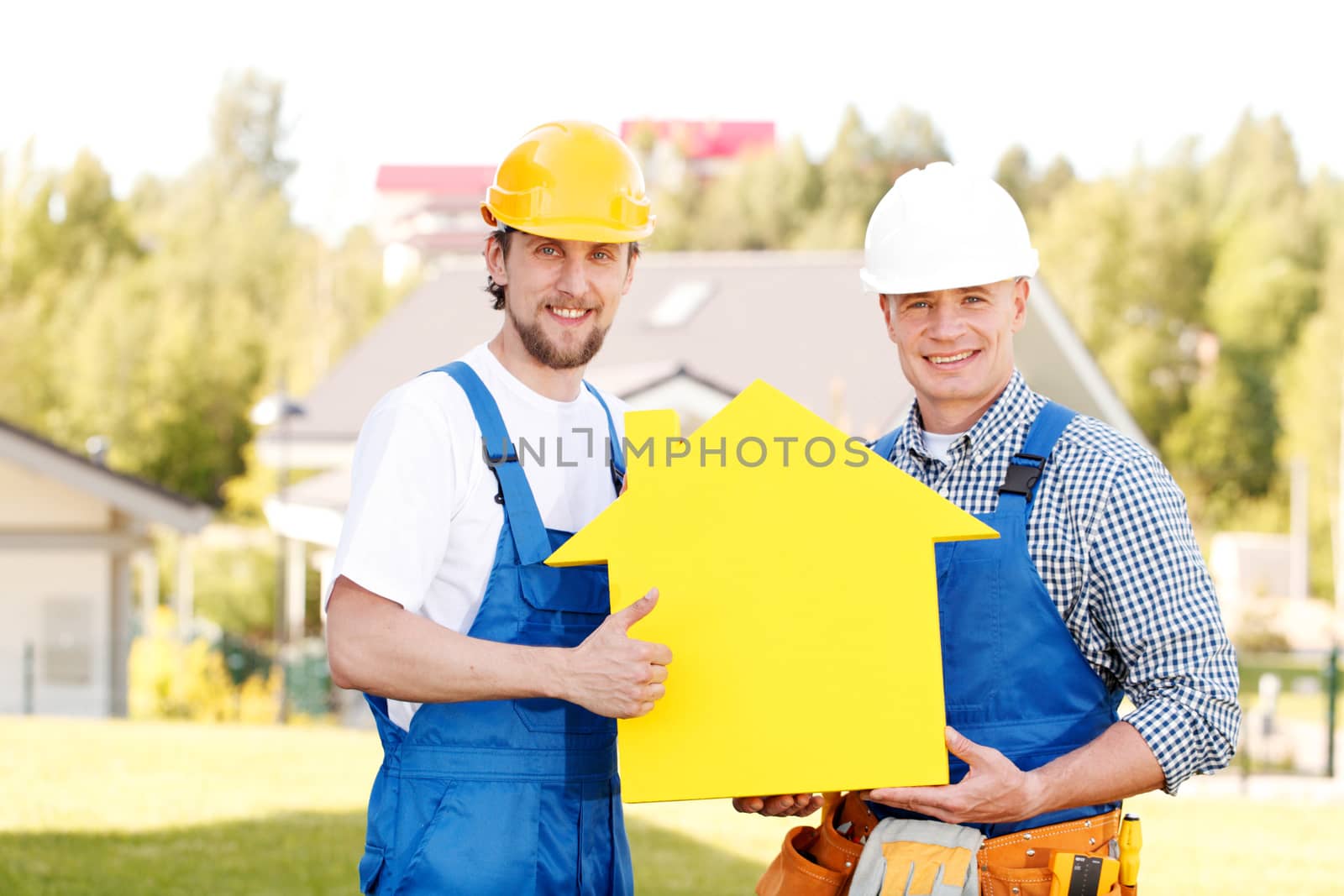 Construction workers showing house model symbol and friendly smiling