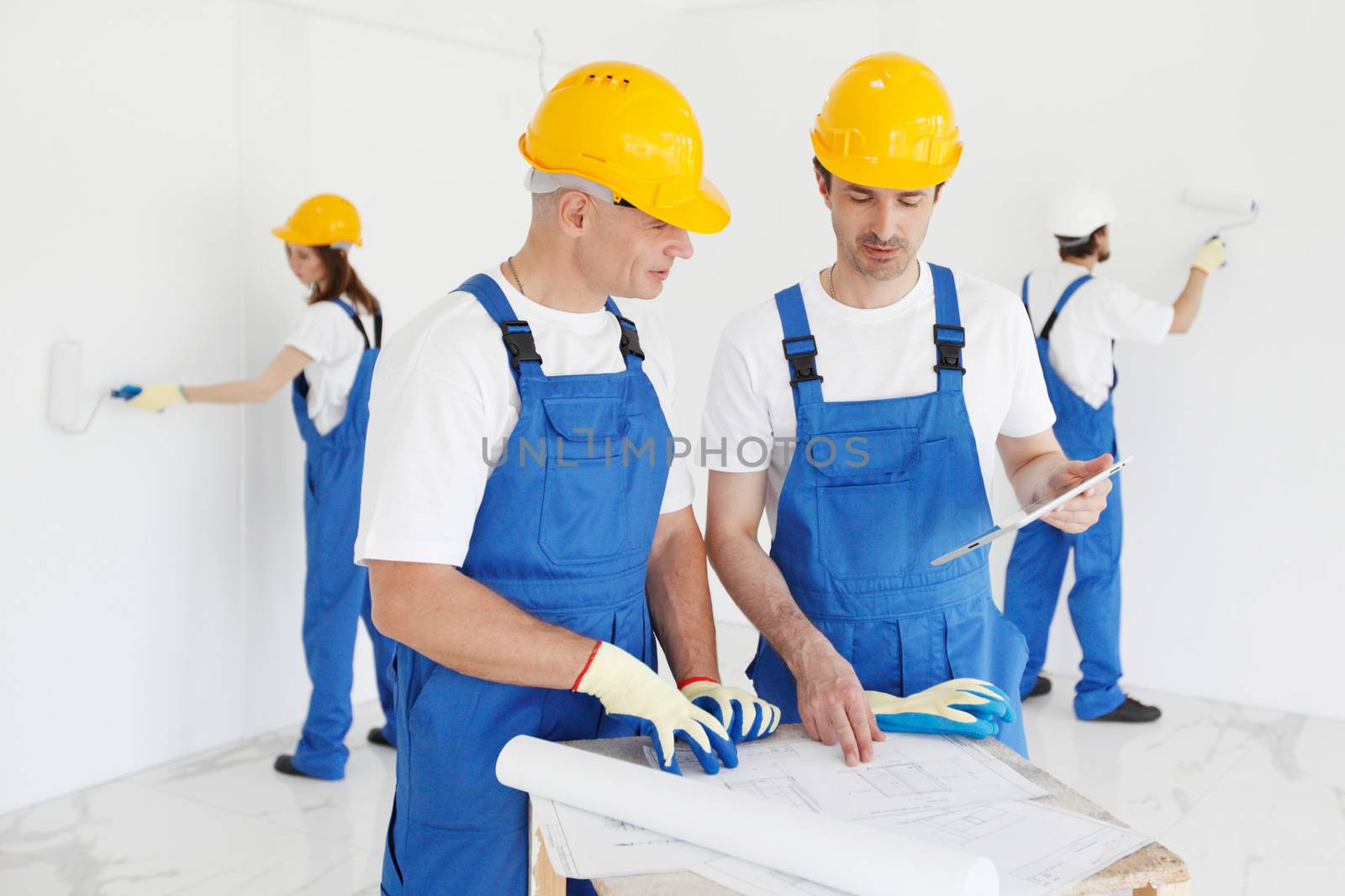 Workers discuss renovation project , two wall painters on background