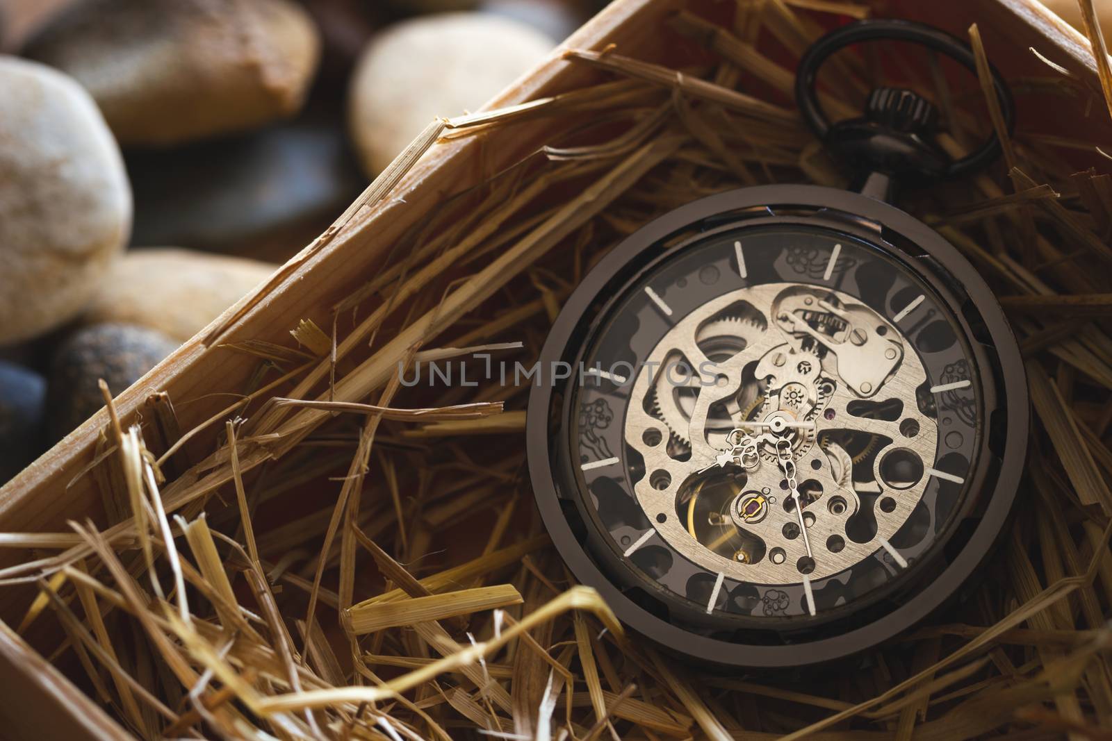 Pocket watch winder on natural wheat straw in a wooden box. Concept of vintage or retro gift.