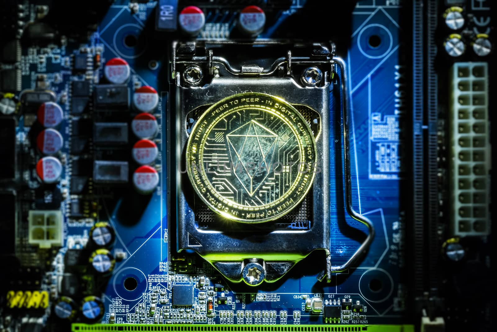 Top view of golden Eos cryptocurrency physical coin on computer mother board processor.Bitcoin mining farm, working computer equipment concept.