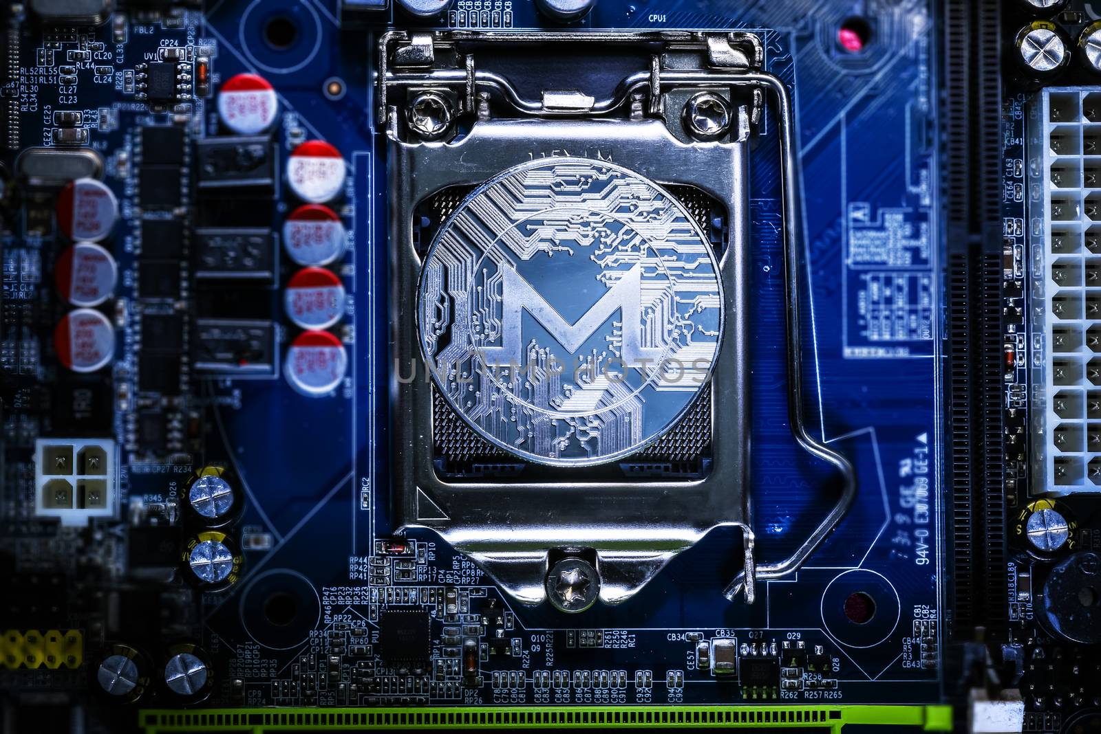 Top view of Monero cryptocurrency physical coin on computer mother board processor.Bitcoin mining farm, working computer equipment concept.