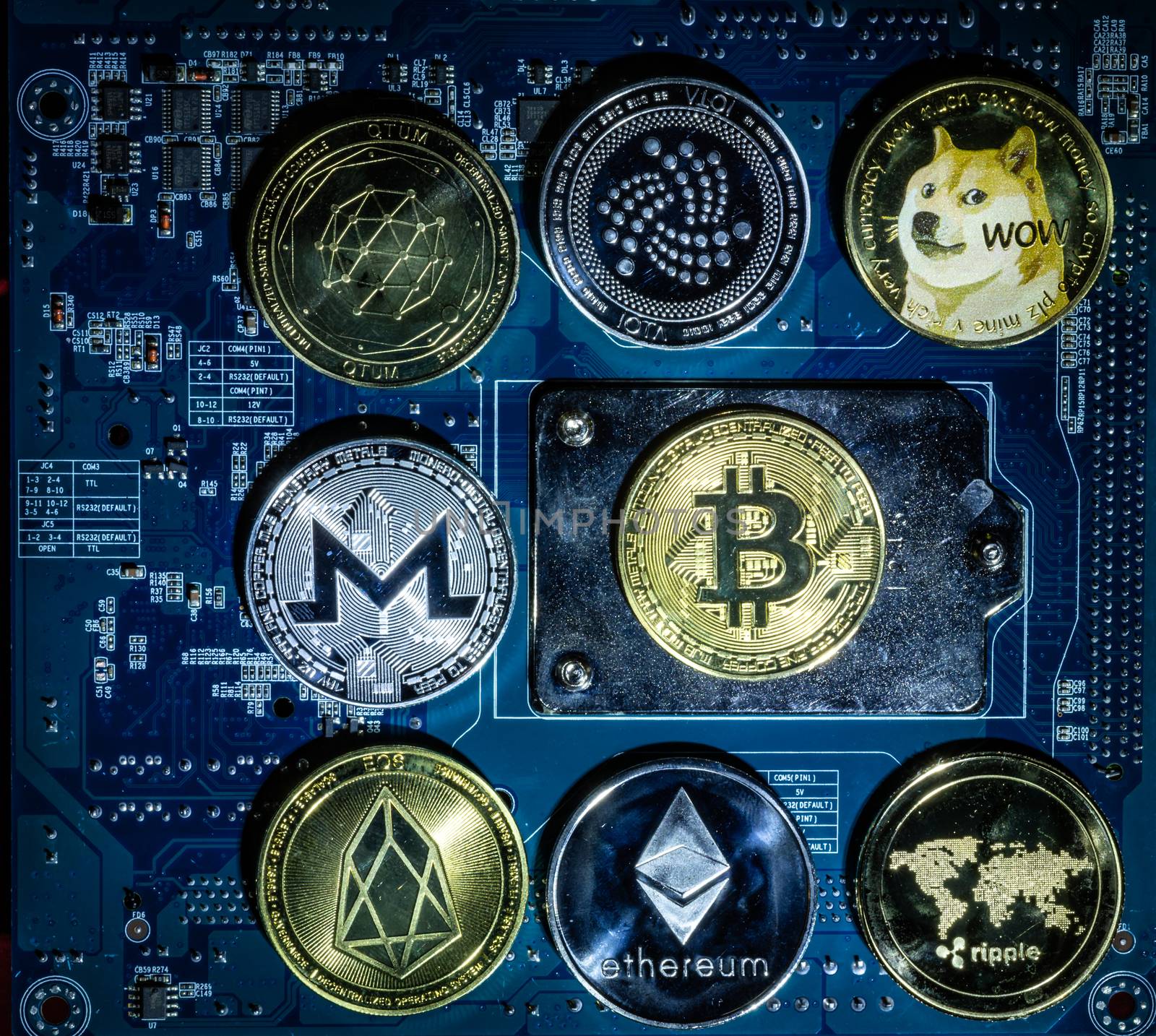 Top view of Bitcoin,Ripple,Ethereum,Eos,Monero,Iota,Dogecoin cryptocurrency physical coins on computer mother board processor.Bitcoin mining farm, working computer equipment concept.