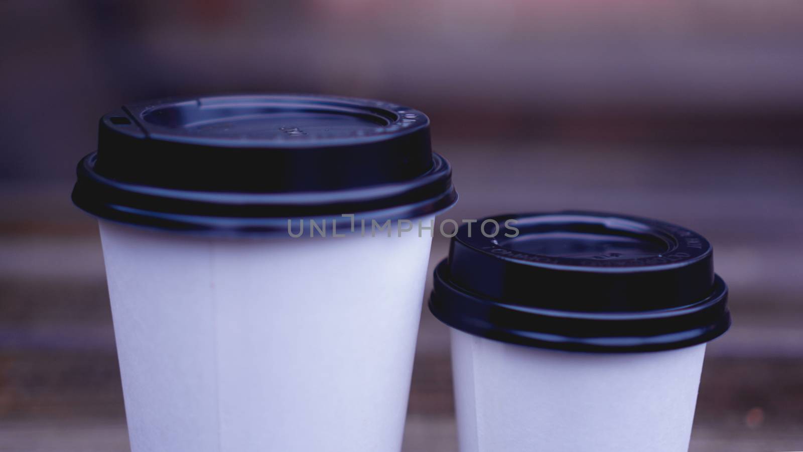 Coffee paper craft cup stands on wooden surface on a blurred background by natali_brill