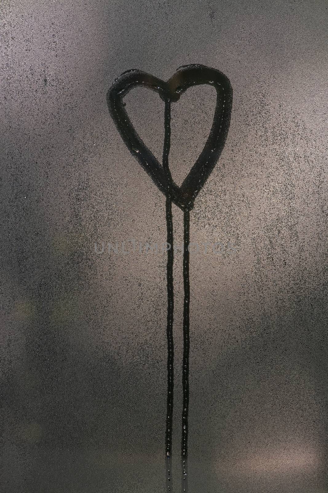 Window dew and drawn heart shape with running drops