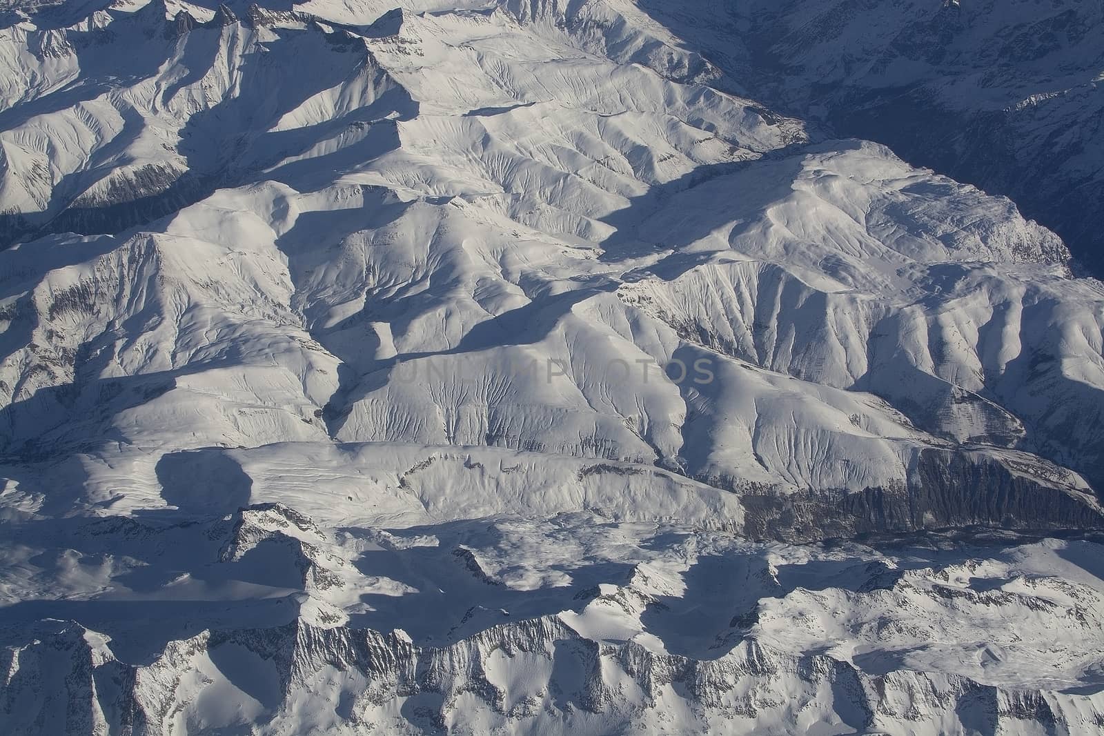 Swiss Alpes with snowy mountain tops aerial view towards the east during afternoon flight in December