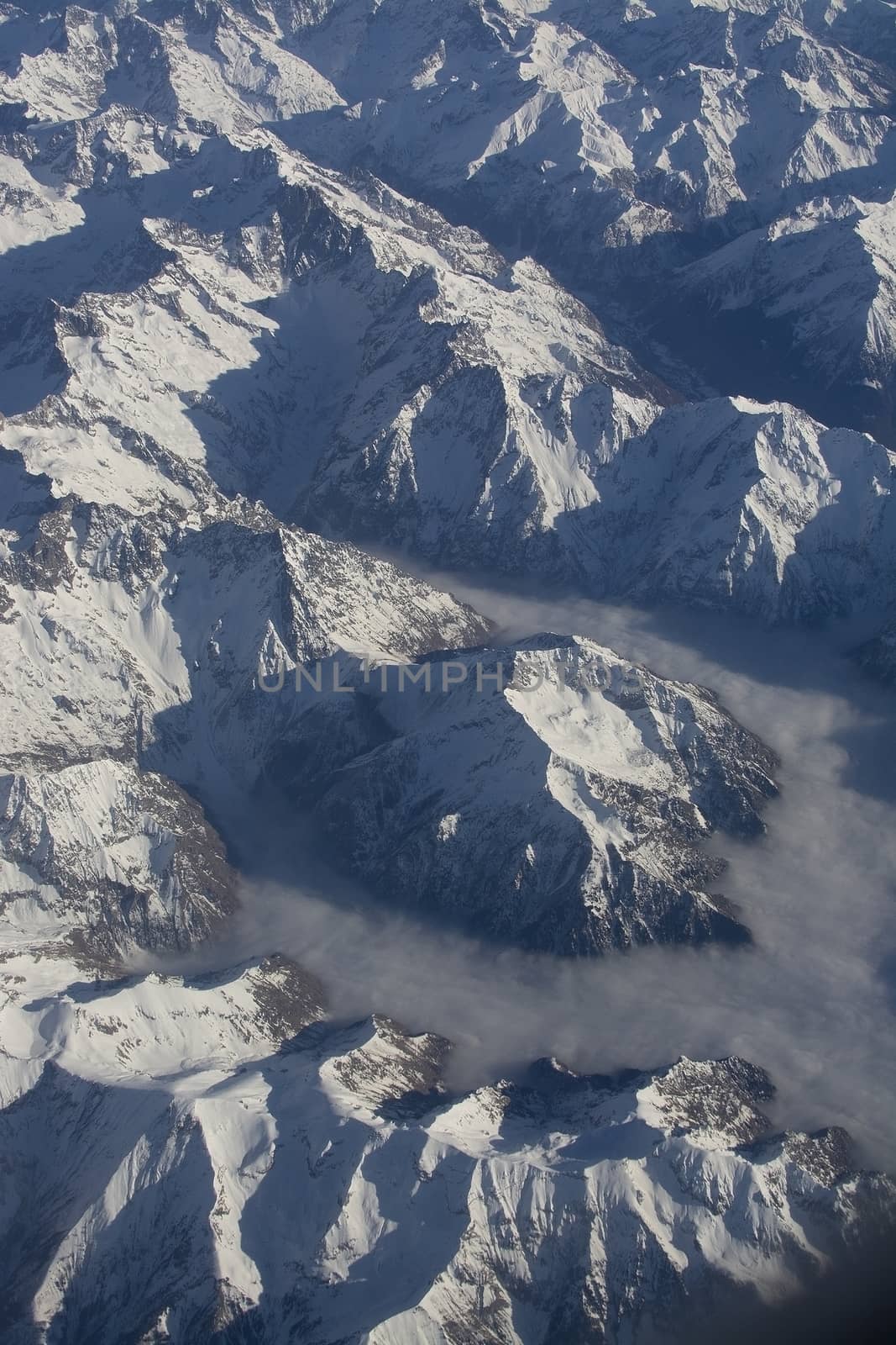 Swiss Alpes with snowy mountain tops aerial view towards the east during afternoon flight in December