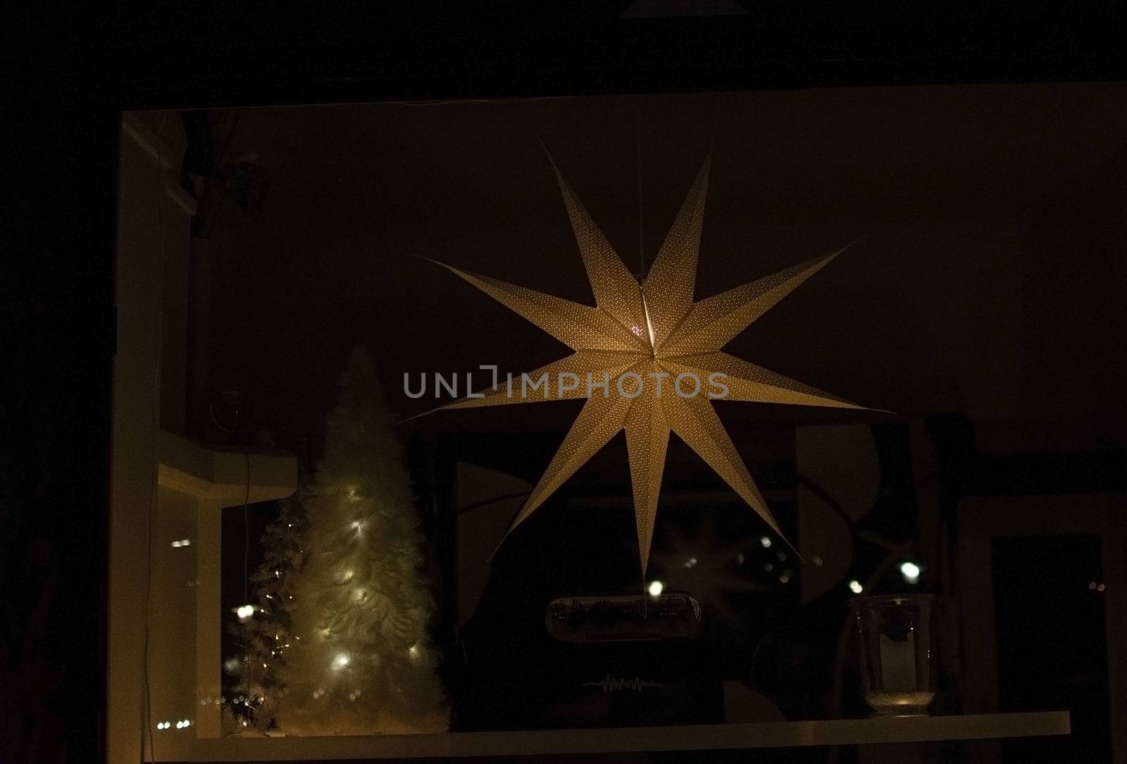 Advent star christmas decorations in window in darkness.