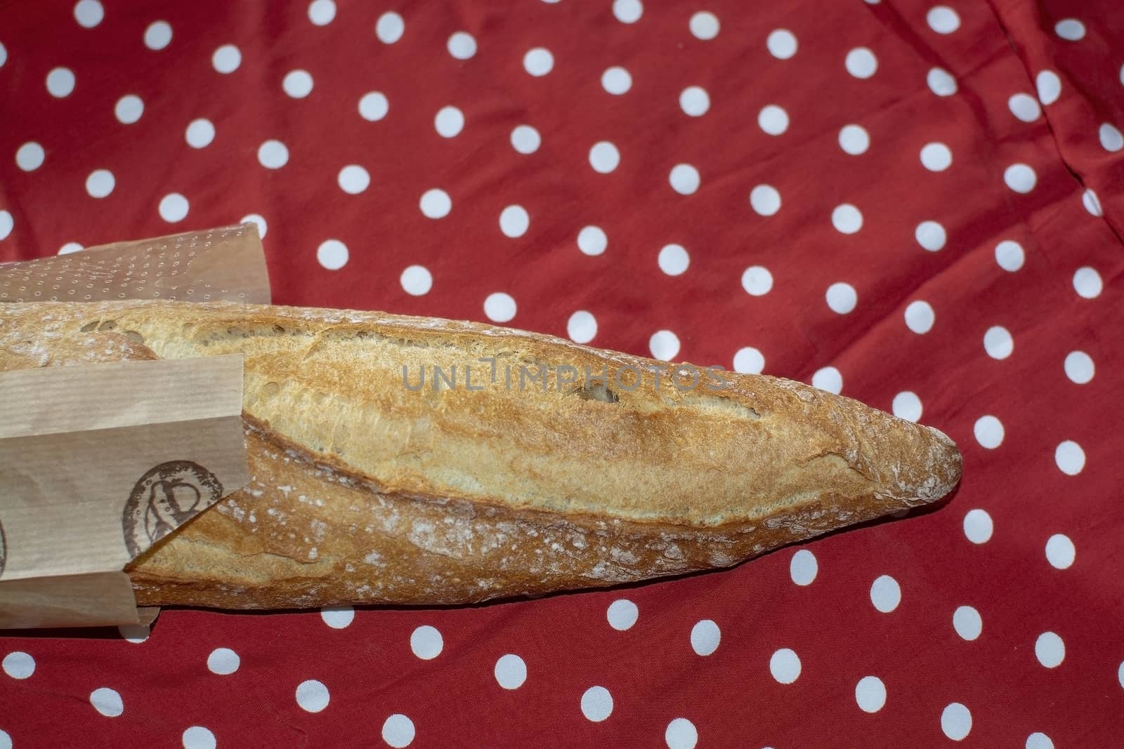 Baguette bread on red and white polka dot fabric decorative background.