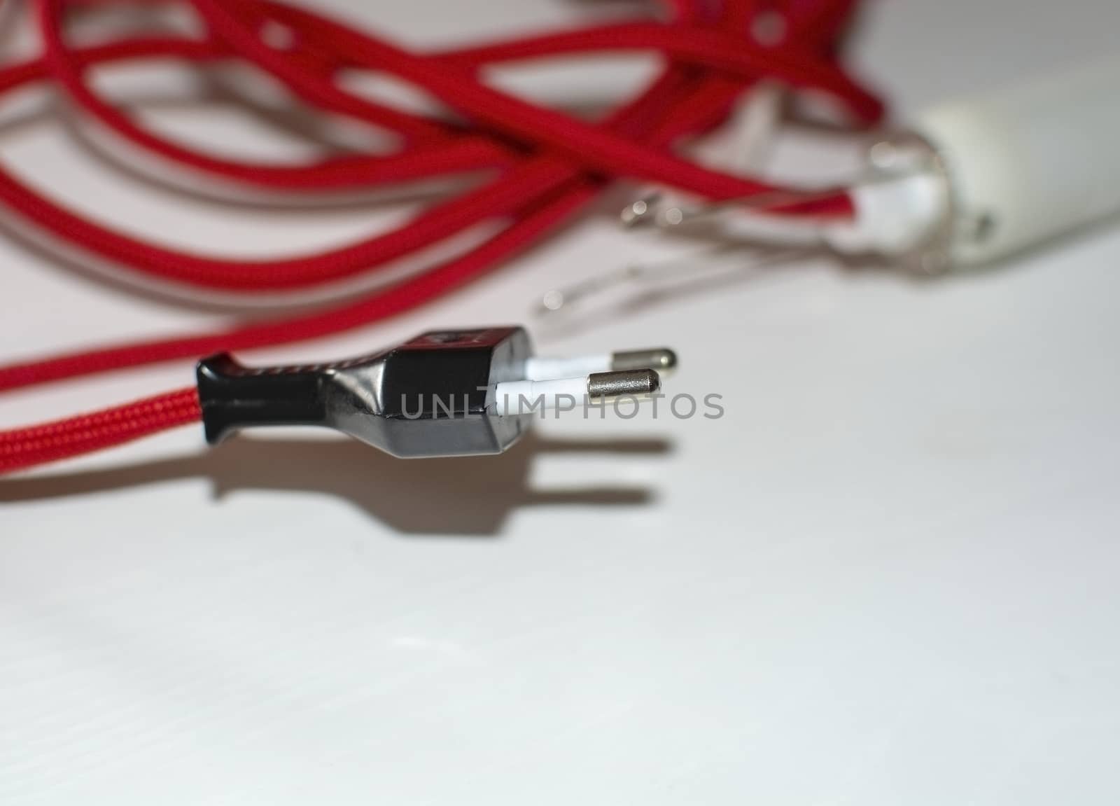 Electricity cord covered in red fabric on white background.