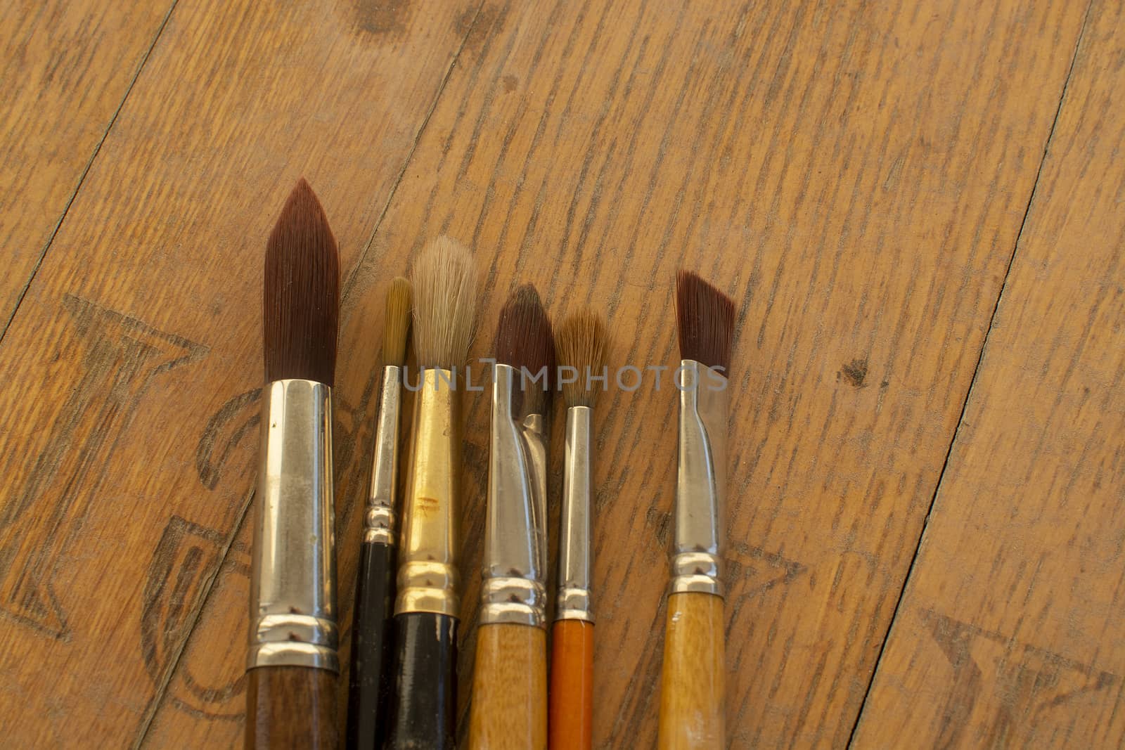 Set of various artist brushes for watercolor painting on old shabby grungy retro vintage wooden background.