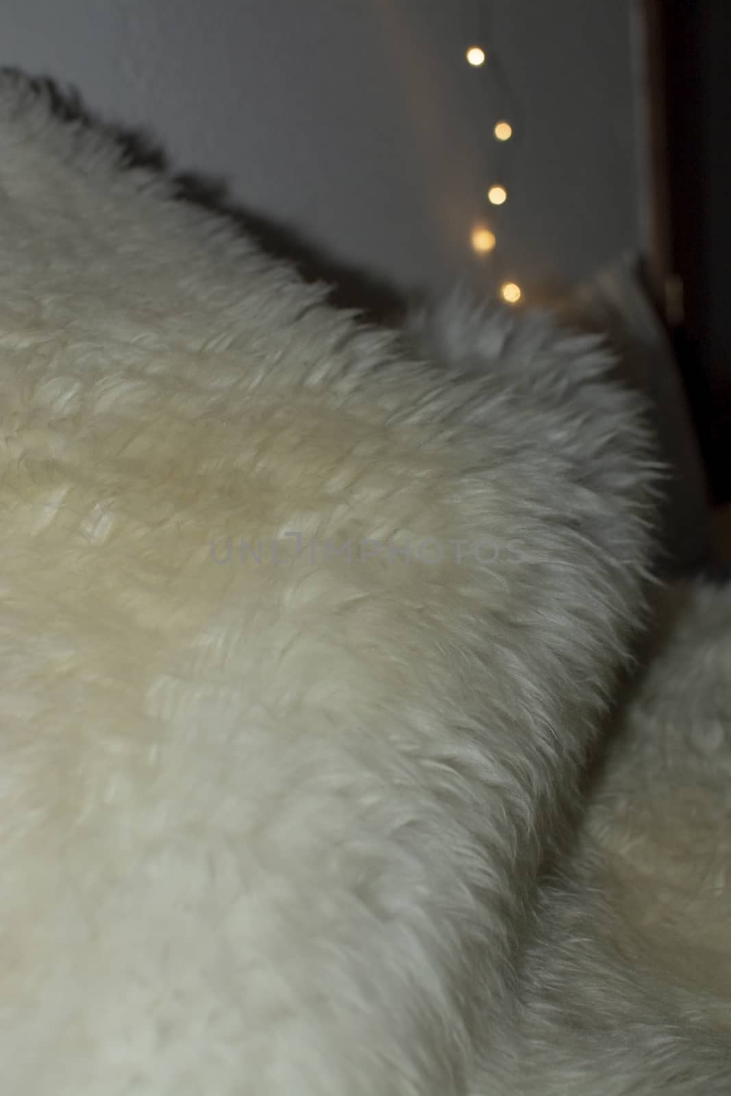 White lambswool fur and bokeh christmas lights winter concept background texture.